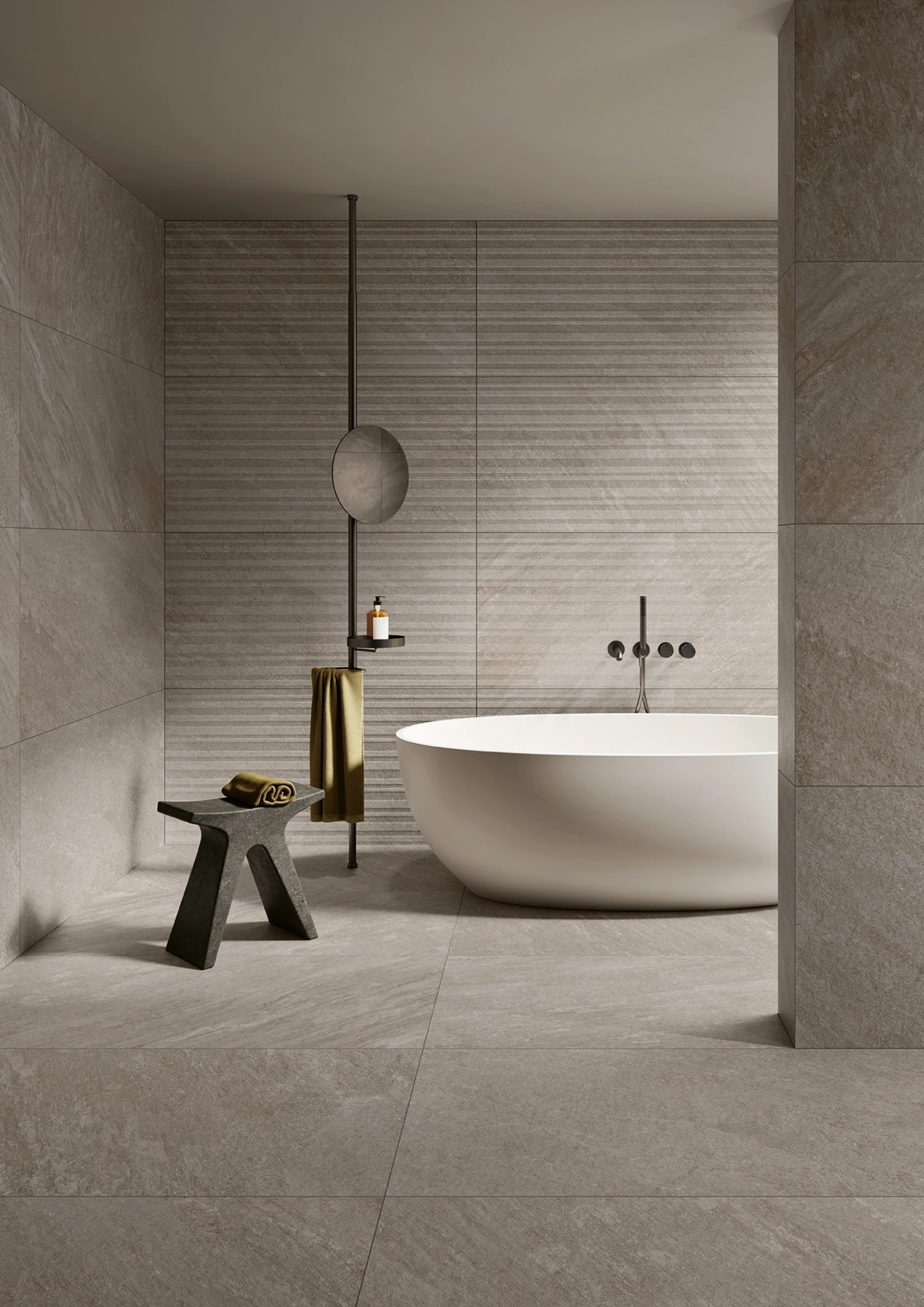 Modern bathroom with freestanding white oval bathtub, stone tile walls, and a towel rack with mirror.