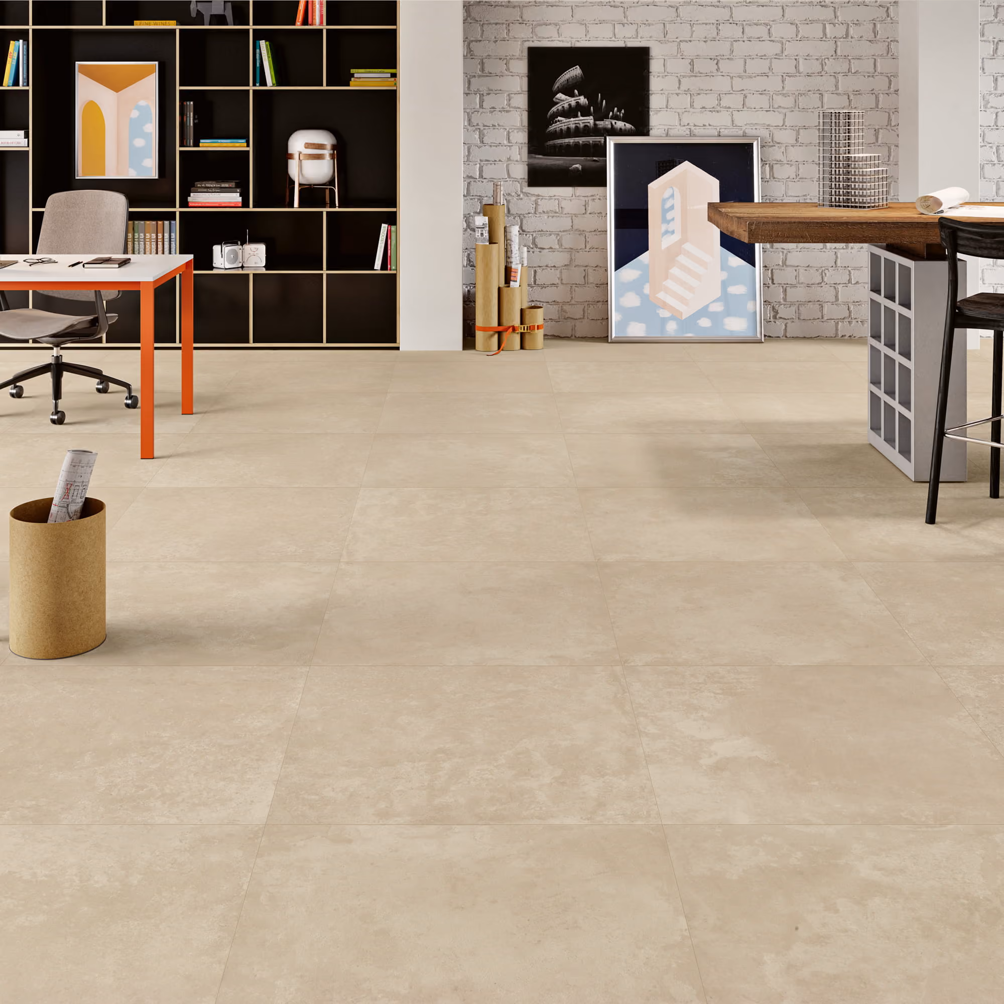 Spacious office interior with beige tiled floor, brick wall, desks, shelves, and framed artwork.