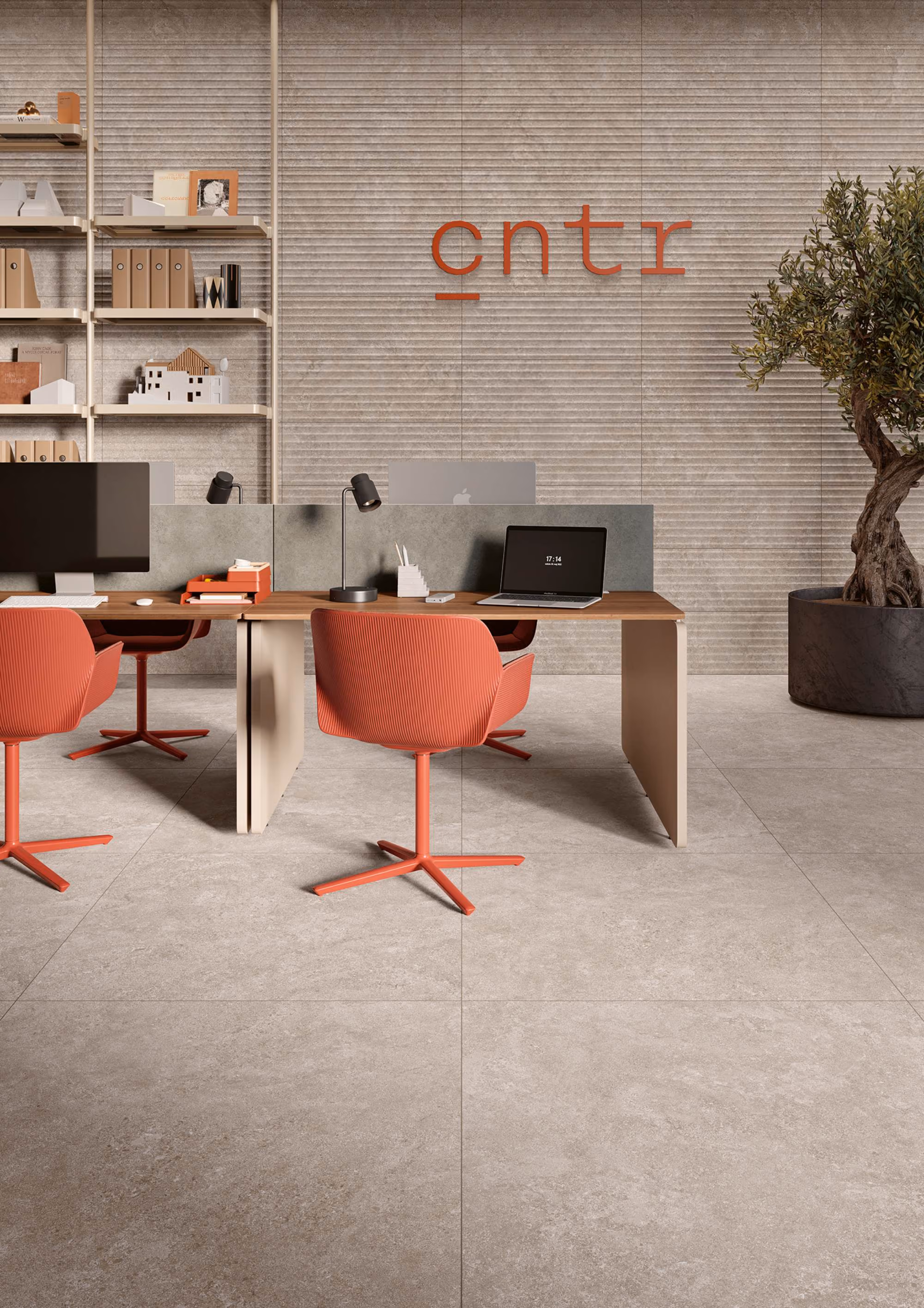 Modern office space with wooden desks, coral chairs, computers, and a potted plant by a tiled wall.