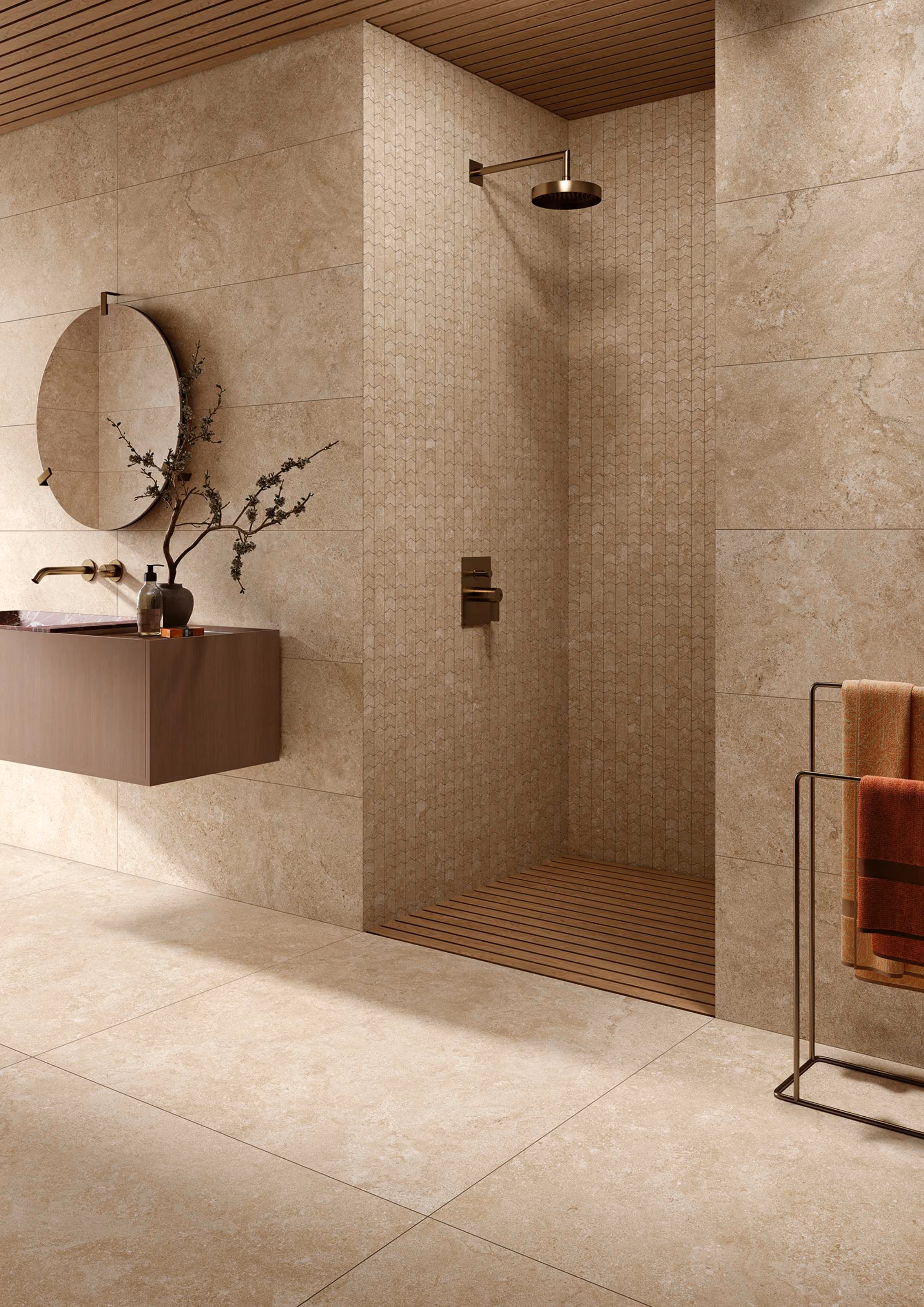 Modern beige bathroom with walk-in shower, round mirror, floating sink, and towel rack with towels.
