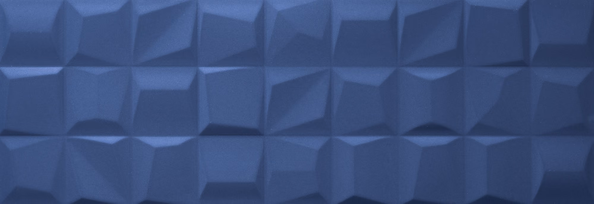Close-up of a textured deep blue surface with geometric, faceted square patterns.
