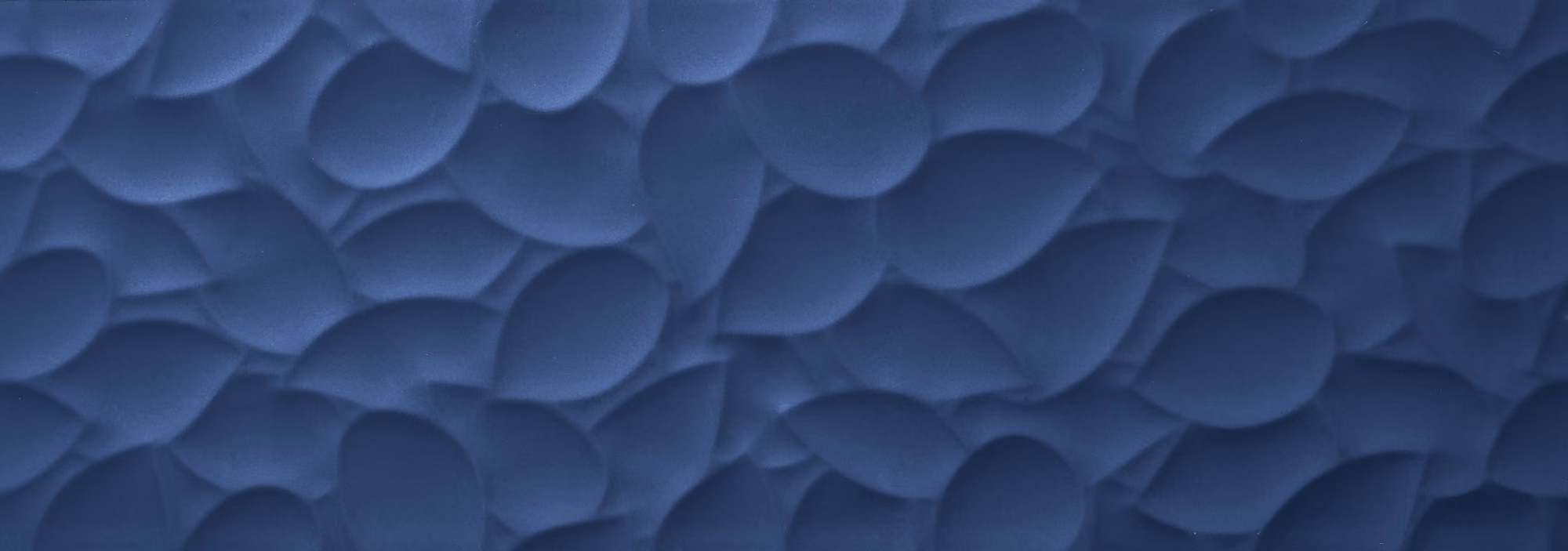 Dark blue surface with raised, abstract leaf-shaped patterns overlapping each other.