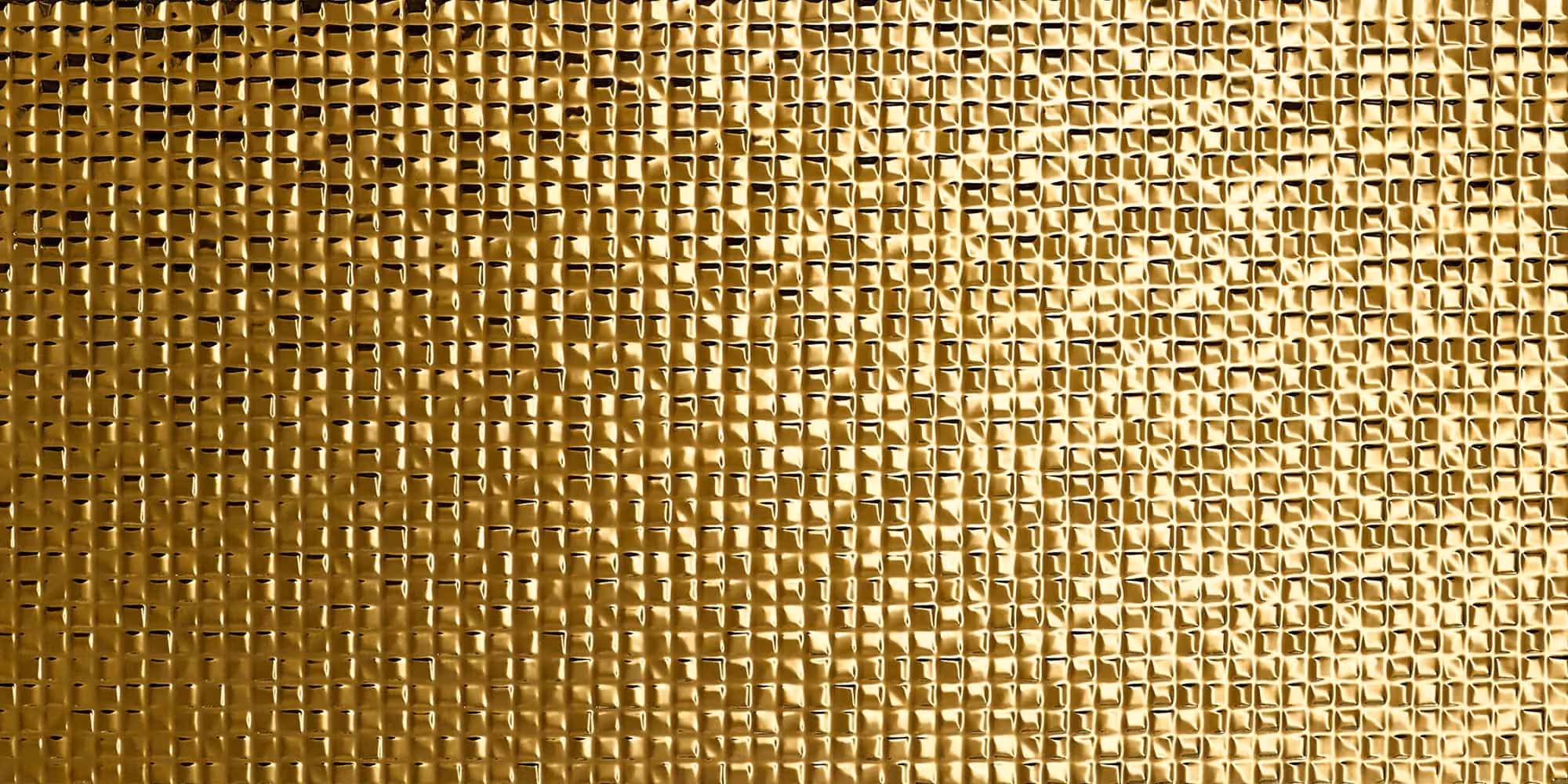 Close-up of a textured gold surface with a grid-like pattern and reflective highlights.
