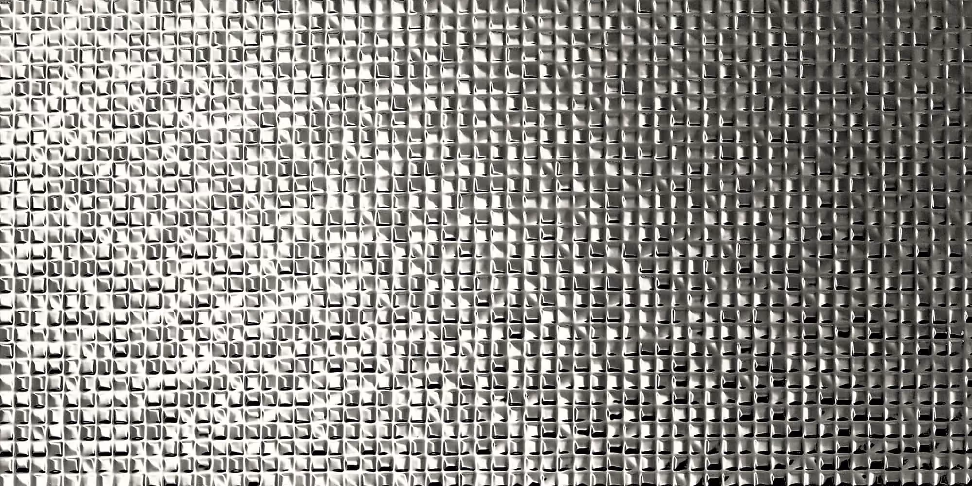 Close-up of a reflective silver textured surface made of small, raised square patterns.