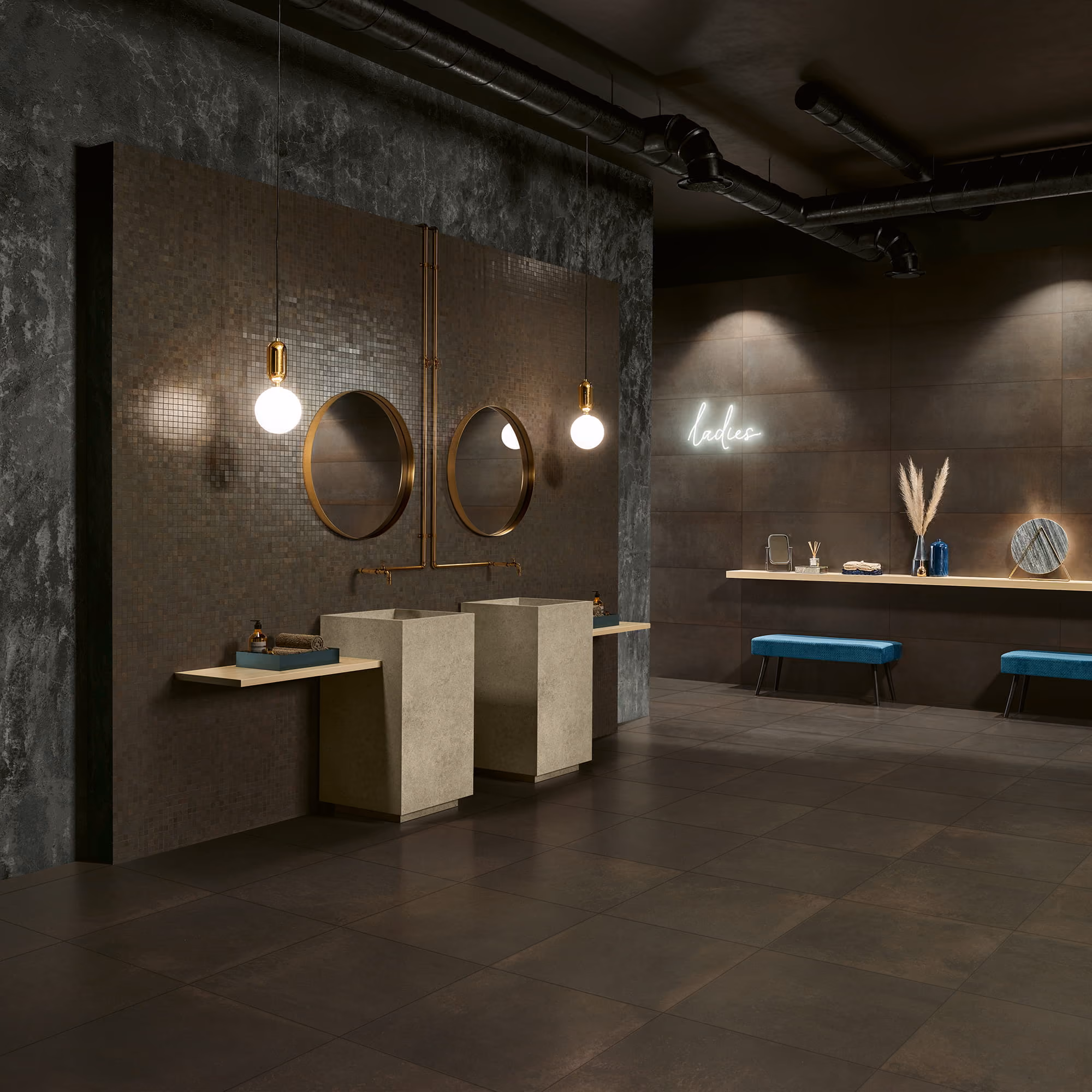 Modern ladies restroom with two pedestal sinks, round mirrors, pendant lights, blue benches, and decorative items.