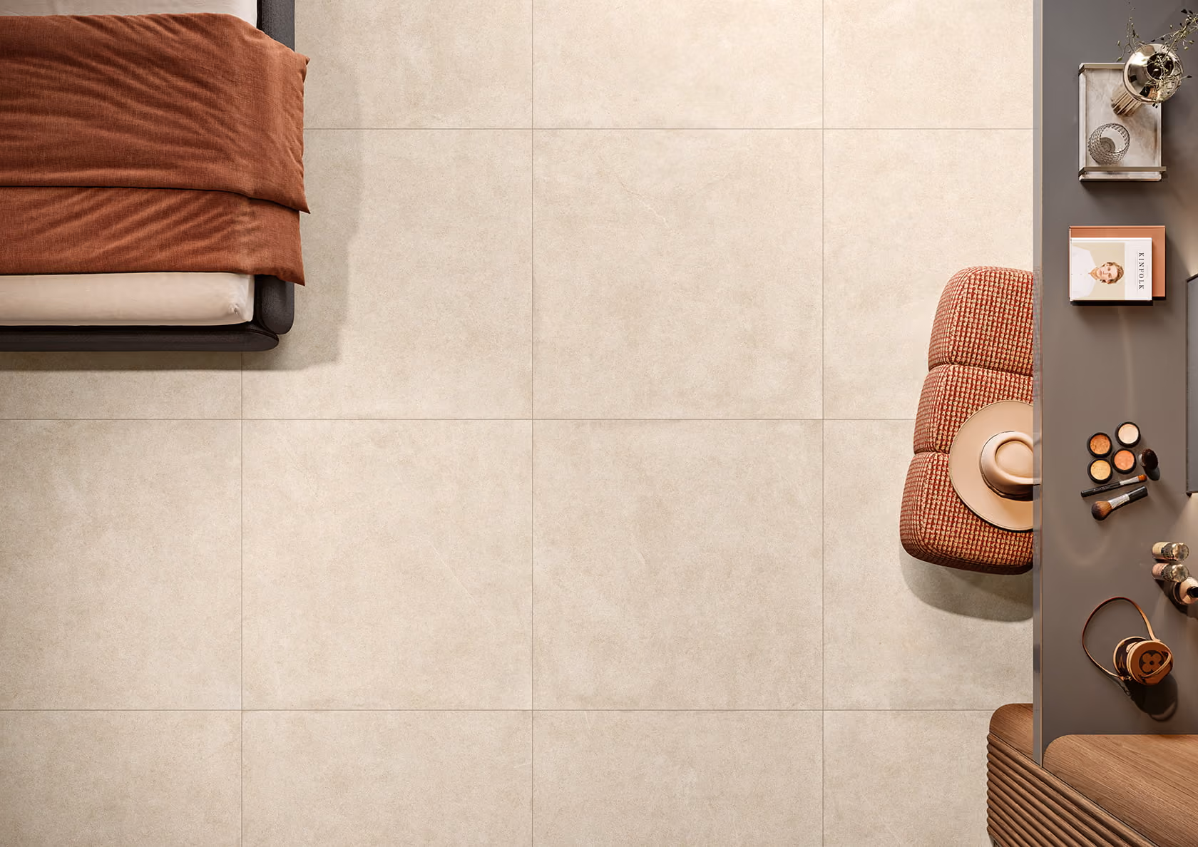 Top view of beige tiled floor with brown bed, cushioned stool, hat, and makeup on a gray desk.