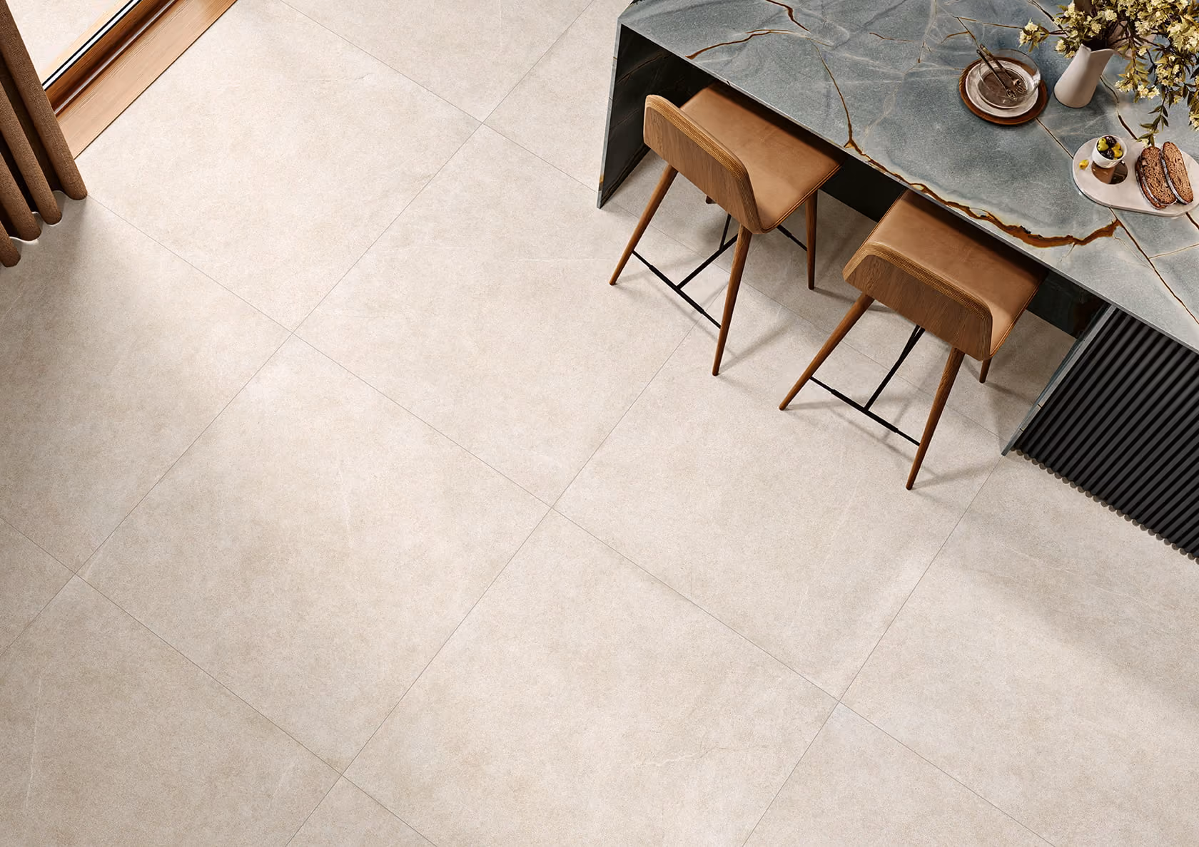 Modern kitchen floor with large beige tiles, two wooden bar stools, and a marble countertop with snacks.