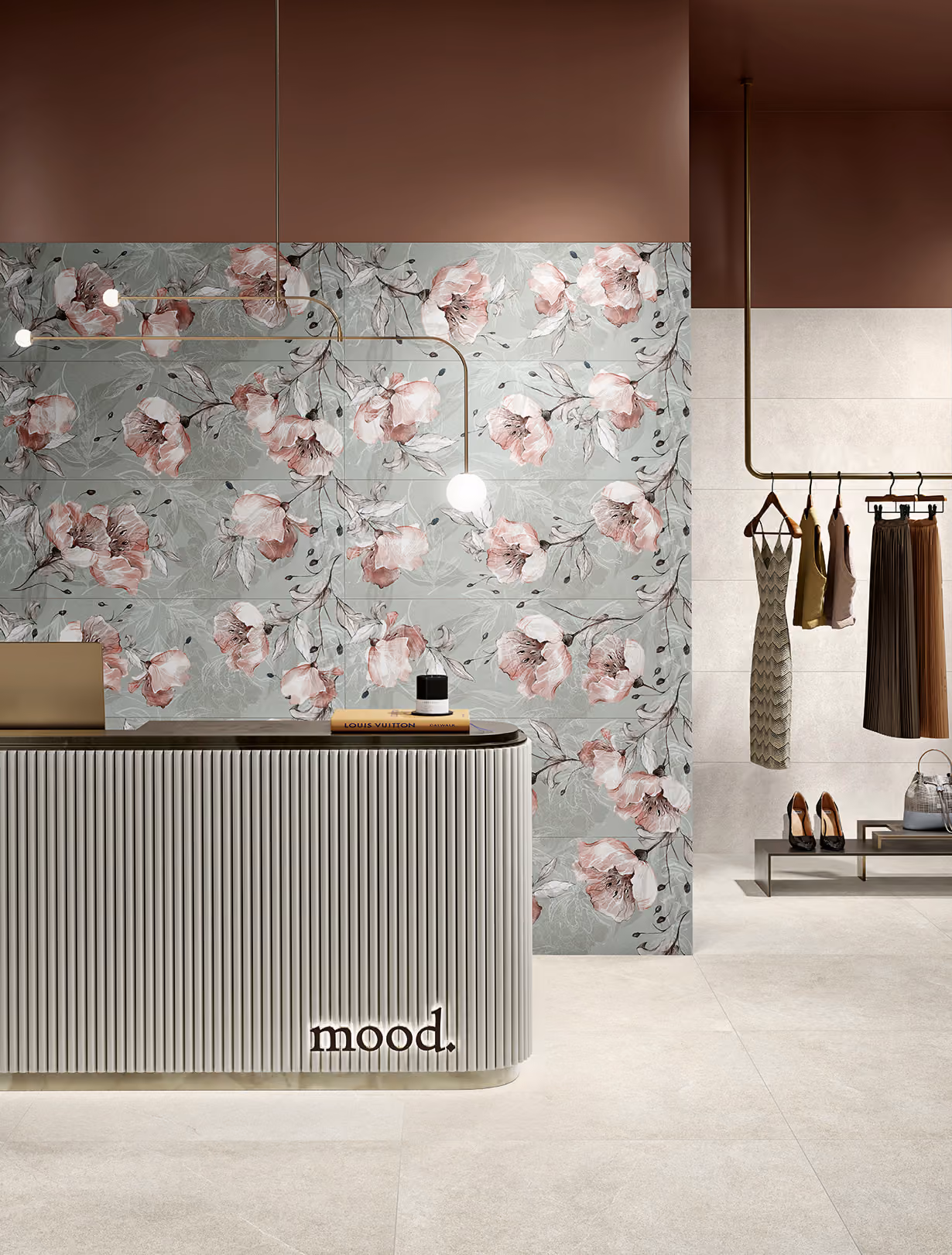 Modern reception desk with 'mood.' sign, floral wall tiles, hanging clothes, and shoes on bench in boutique.