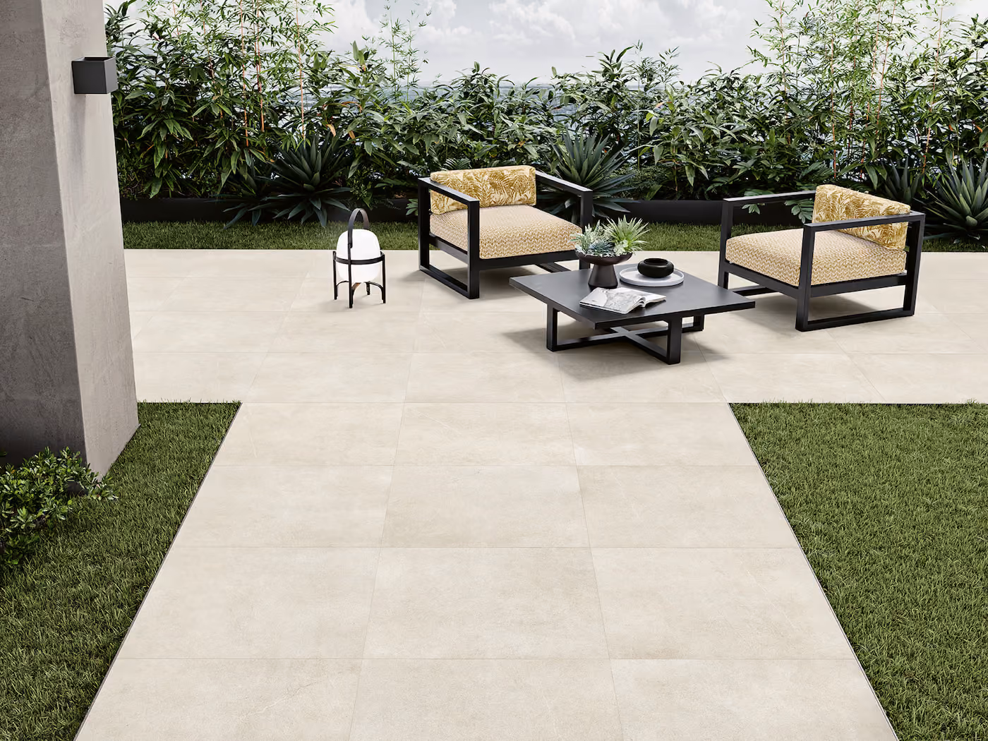 Outdoor patio with two cushioned chairs, a black coffee table, and plants in the background.