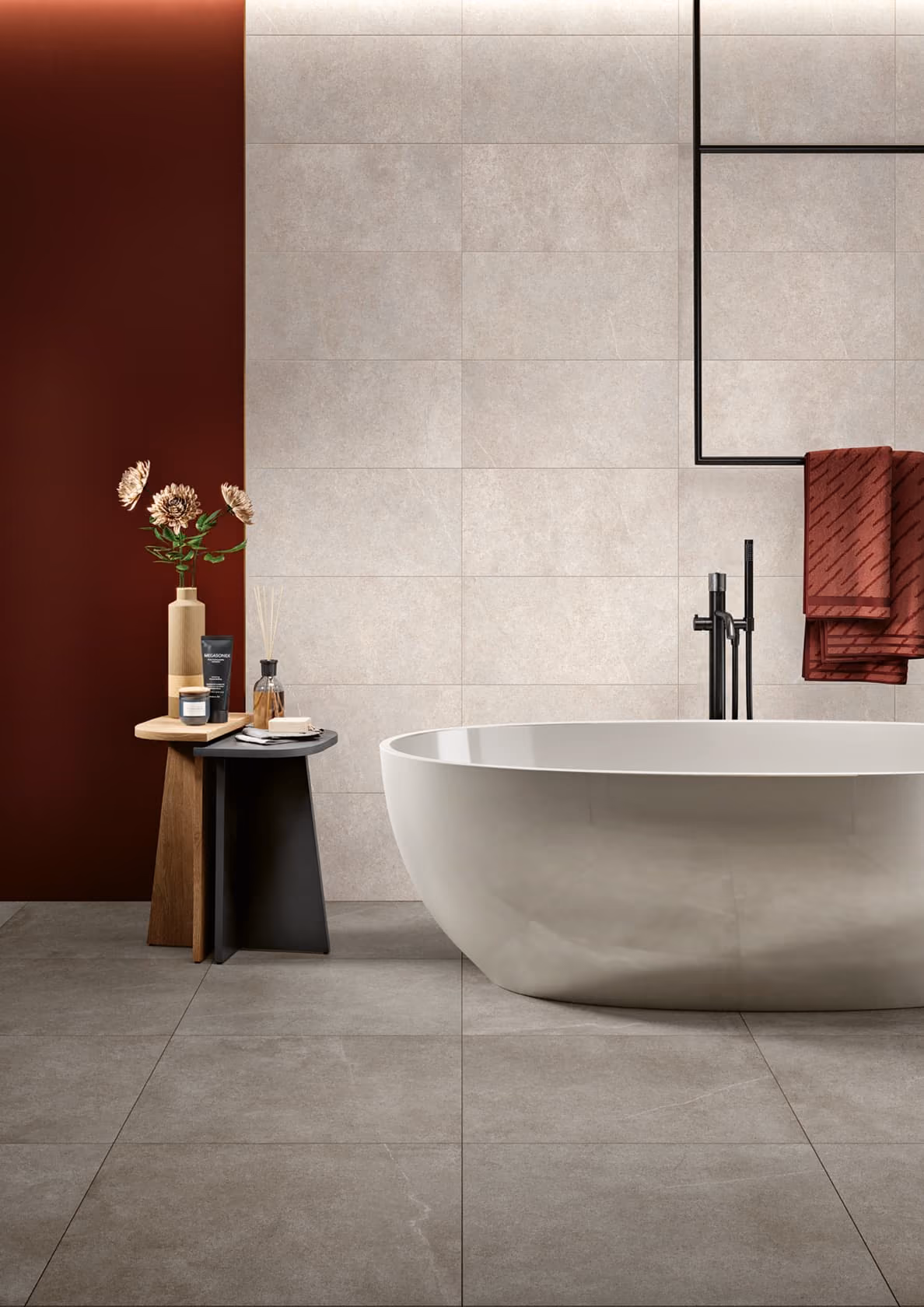 Modern bathroom with freestanding tub, two side tables holding decor, and a towel hanging from a black rack.