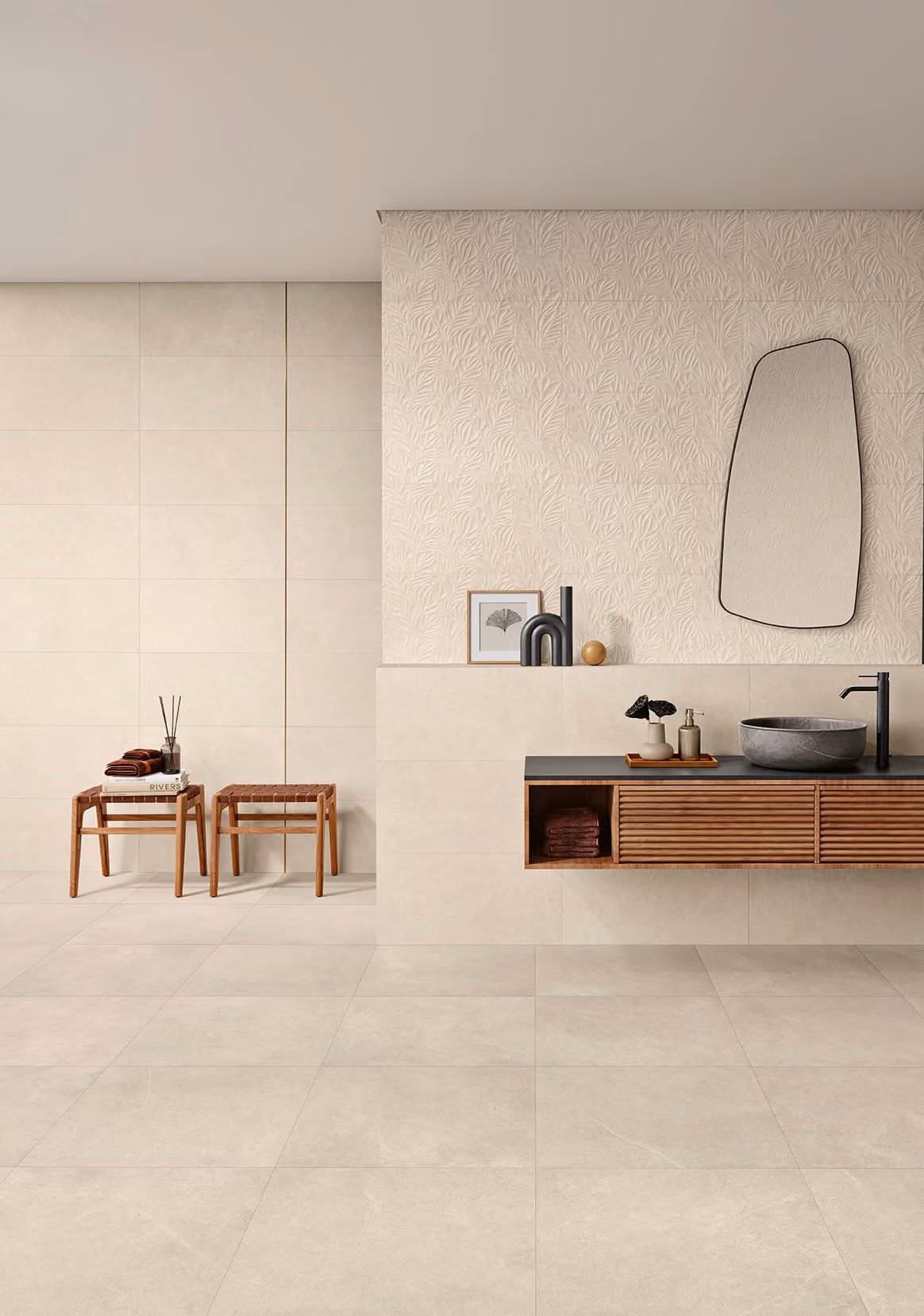 Modern bathroom with beige tiled walls and floor, wooden vanity, round sink, and abstract mirror.
