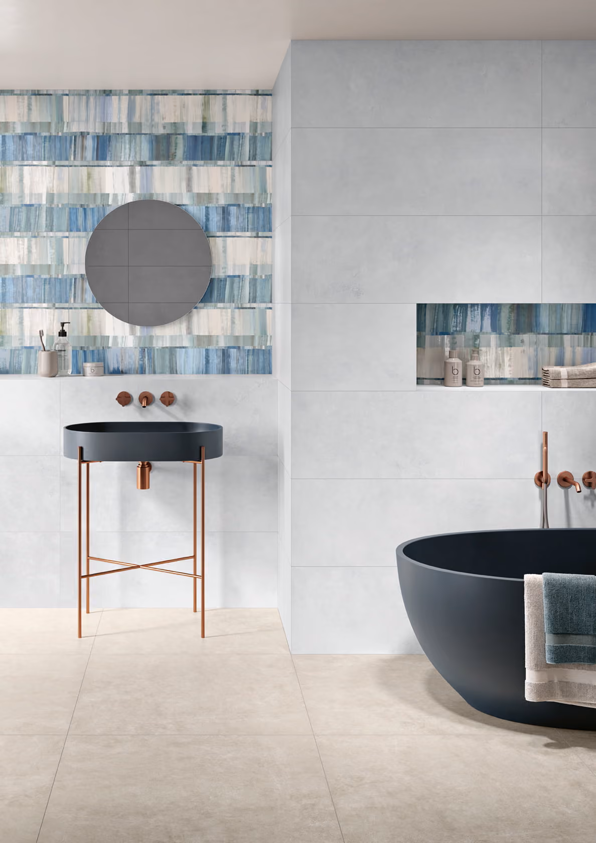 Modern bathroom with a black bathtub and sink, copper fixtures, and blue patterned wall tiles.