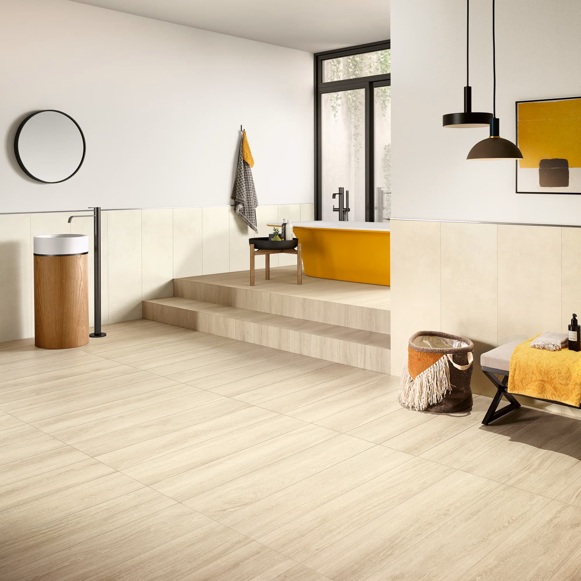 Modern bathroom with light wood flooring, yellow bathtub, round mirror, and decorative towels.