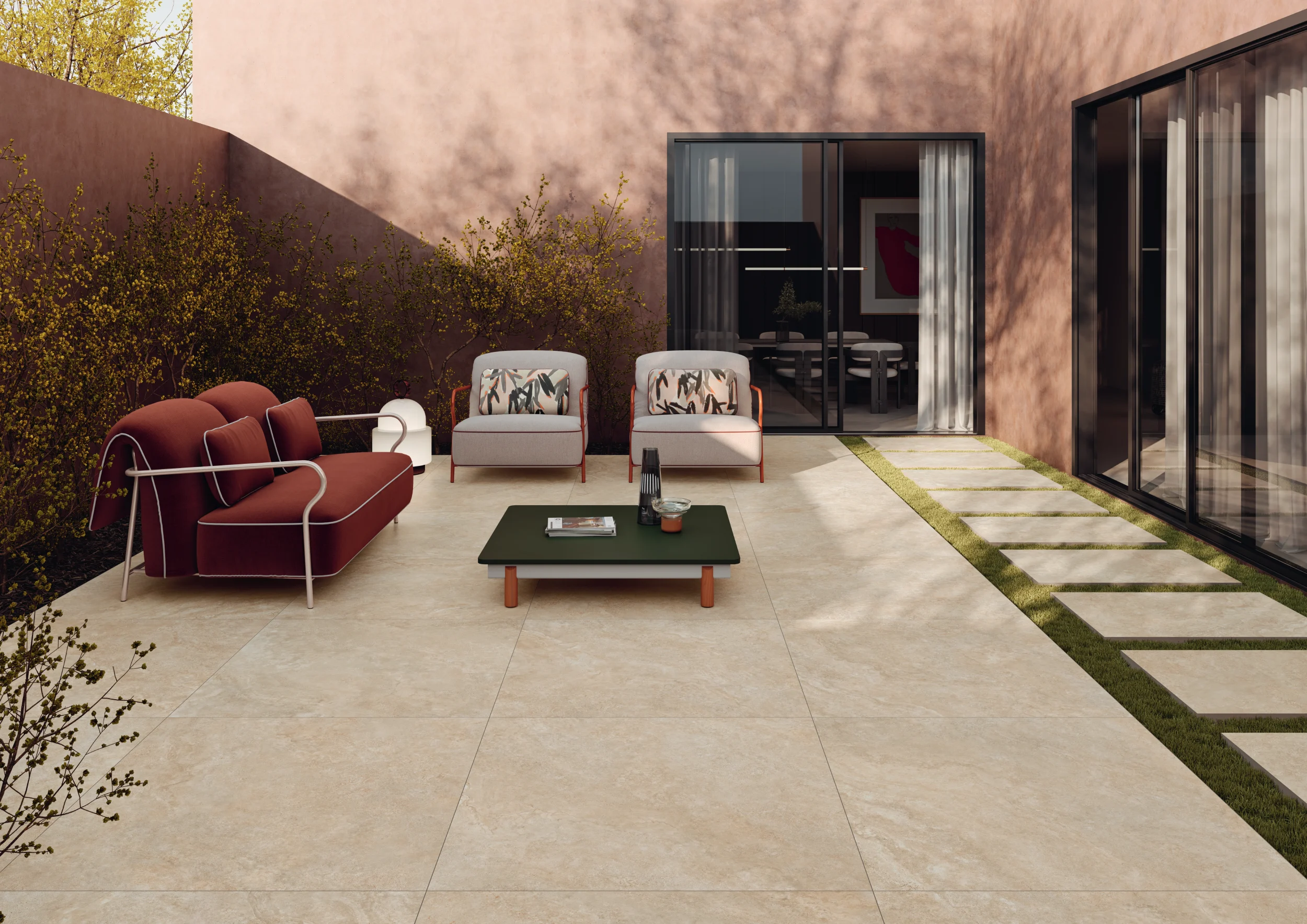 Modern outdoor patio with beige tile floor, a red sofa, two armchairs, and a low green table.