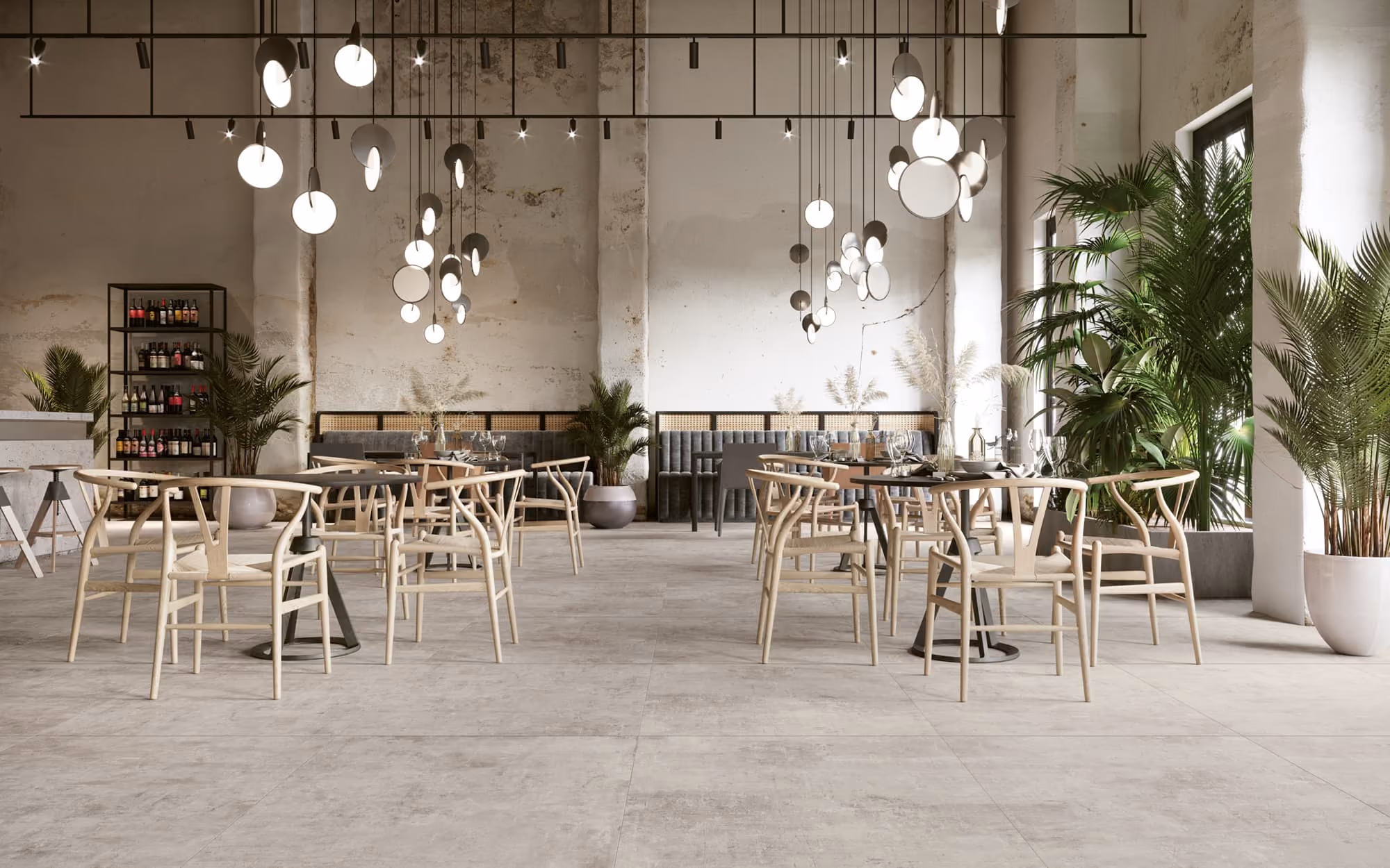 Bright modern restaurant interior with round tables, light wooden chairs, hanging lights, and green plants.
