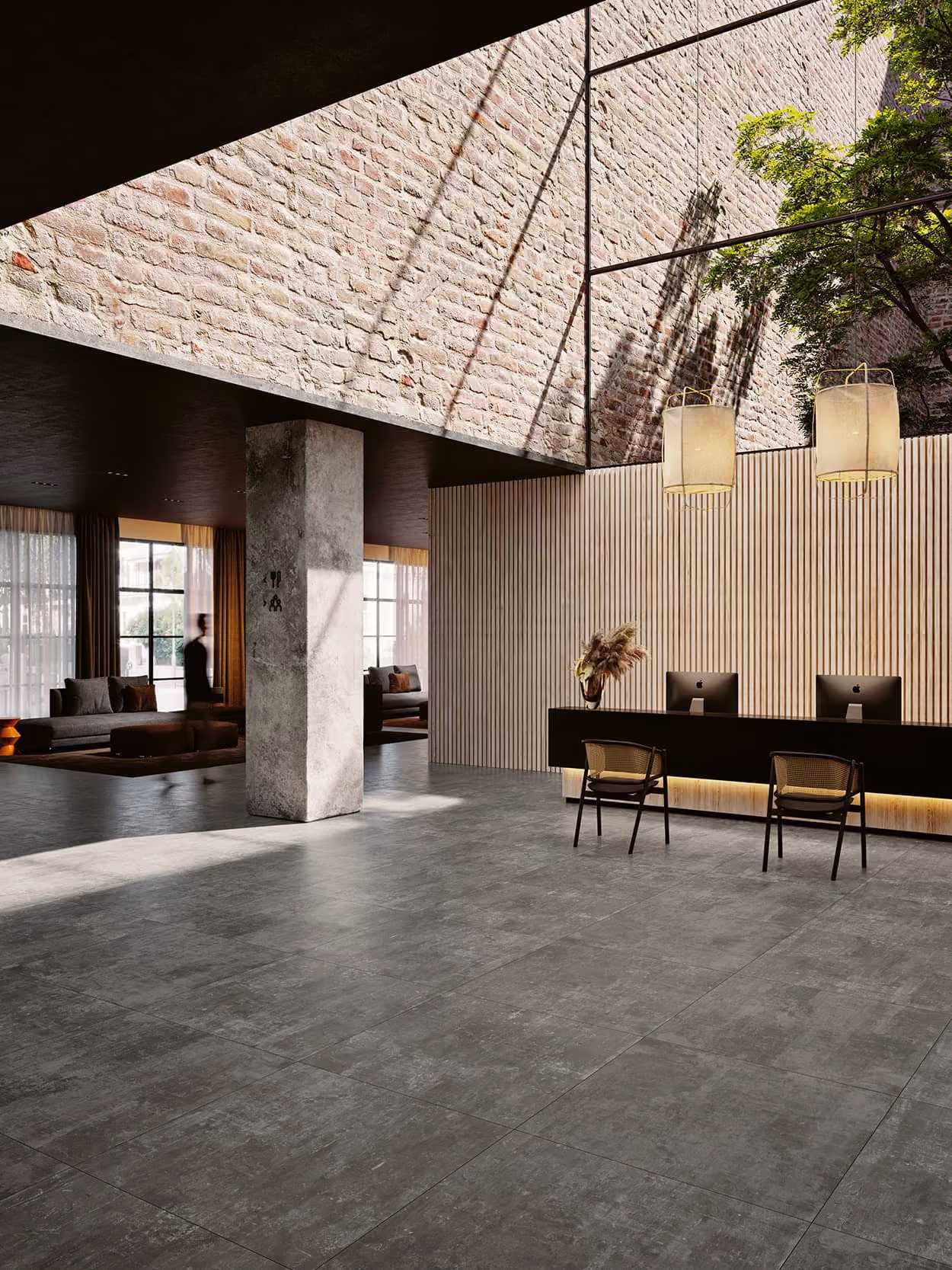 Modern spacious lobby with gray tiled floor, brick wall, black reception desk, two chairs, and hanging lights.