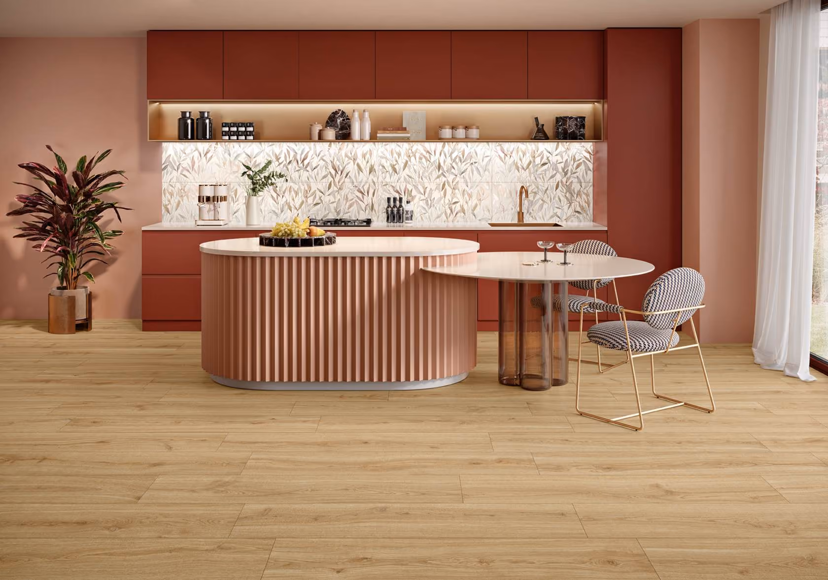 Modern kitchen with dusty pink cabinets, patterned backsplash, island, and two patterned chairs by a round table.