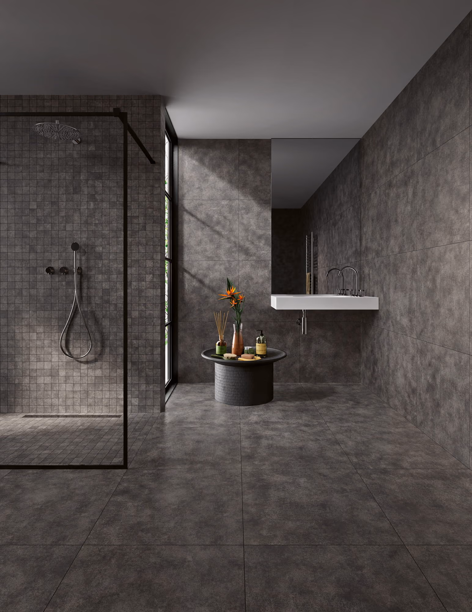 Modern bathroom with gray tiled floors and walls, walk-in shower, floating sink, and round table with decor.