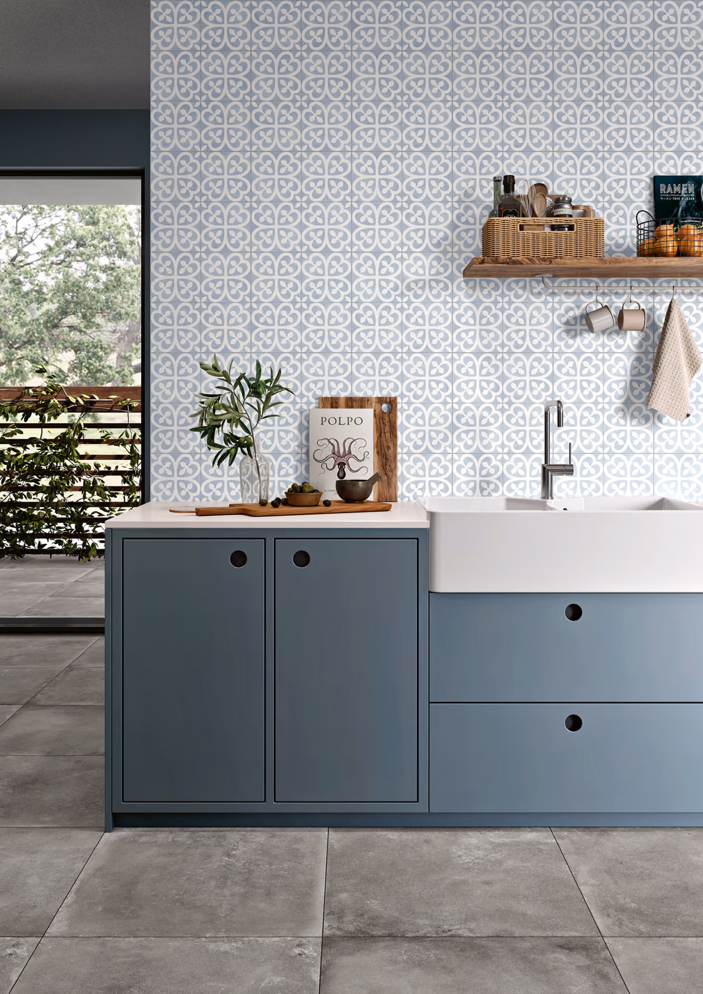 Modern kitchen with blue cabinets, white farmhouse sink, patterned tile backsplash, and wooden shelf with kitchen items.