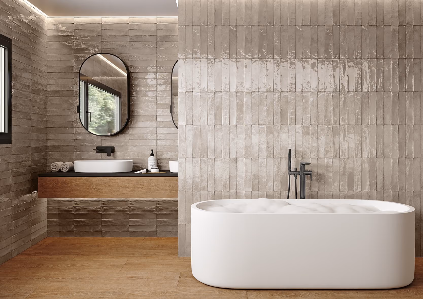 Modern bathroom with a white freestanding tub, beige tiled walls, wood floor, and black-framed oval mirror.