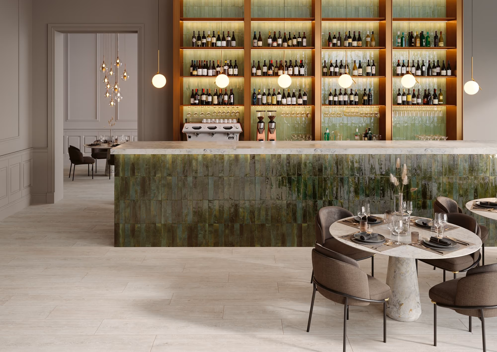 Modern bar with green tiled counter, marble top, shelves of wine bottles, and dining tables with set glasses.