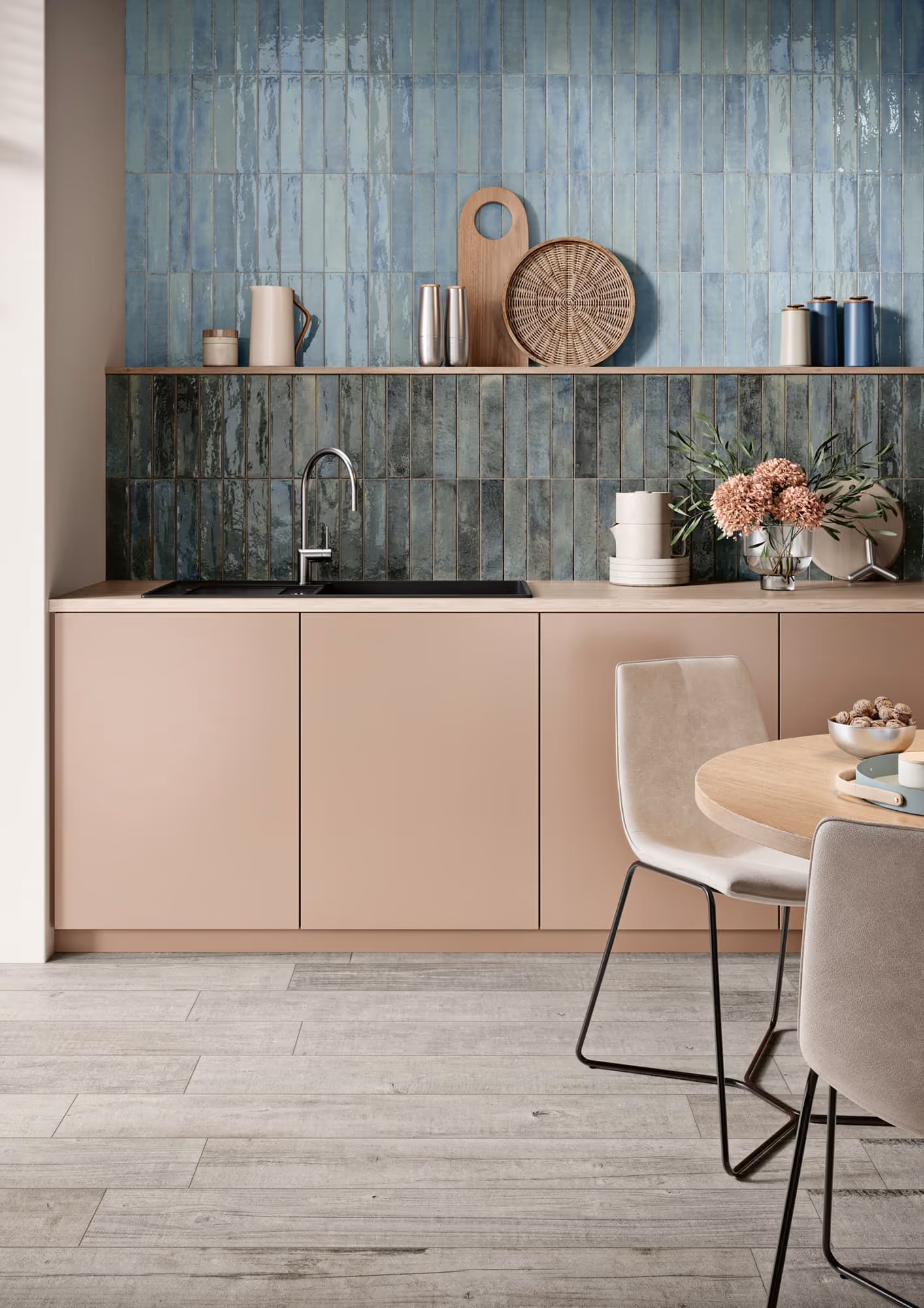 Modern kitchen with beige cabinets, blue-green tiled backsplash, sink, and dining table with chairs.