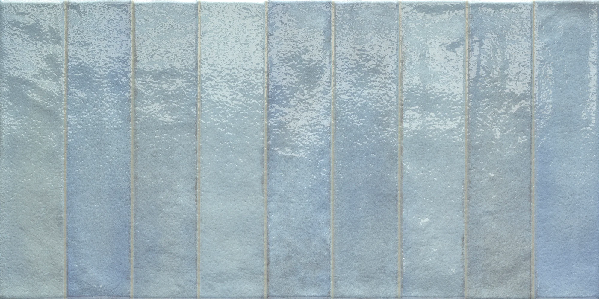 Glossy ceramic tiles in vertical rectangular stripes of varying light blue shades with subtle texture.