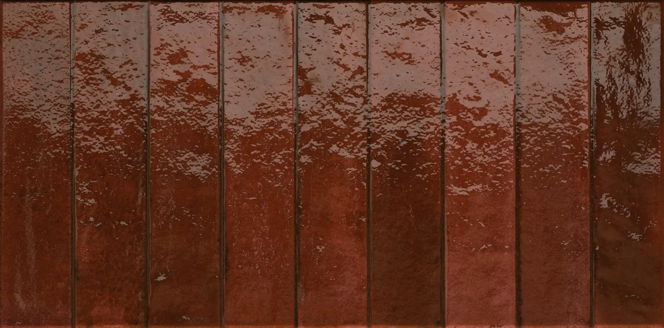 Close-up of glossy dark red rectangular ceramic tiles arranged in a grid pattern.