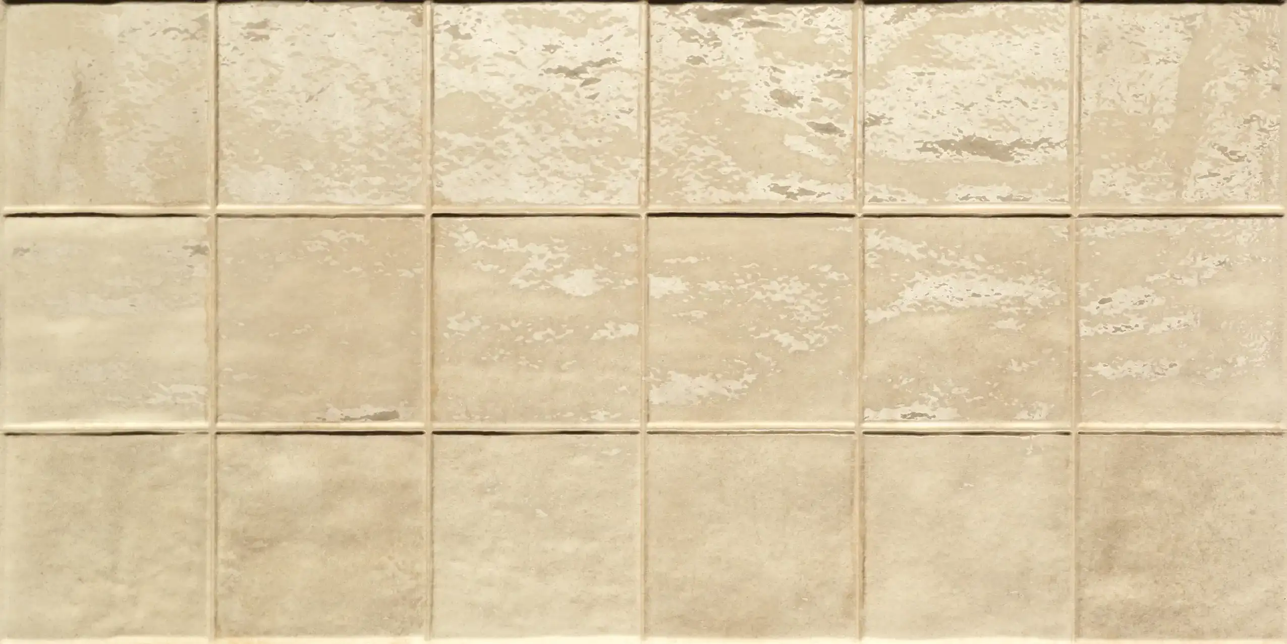 Rectangular beige ceramic wall tiles with varying matte and glossy finishes in a grid layout.