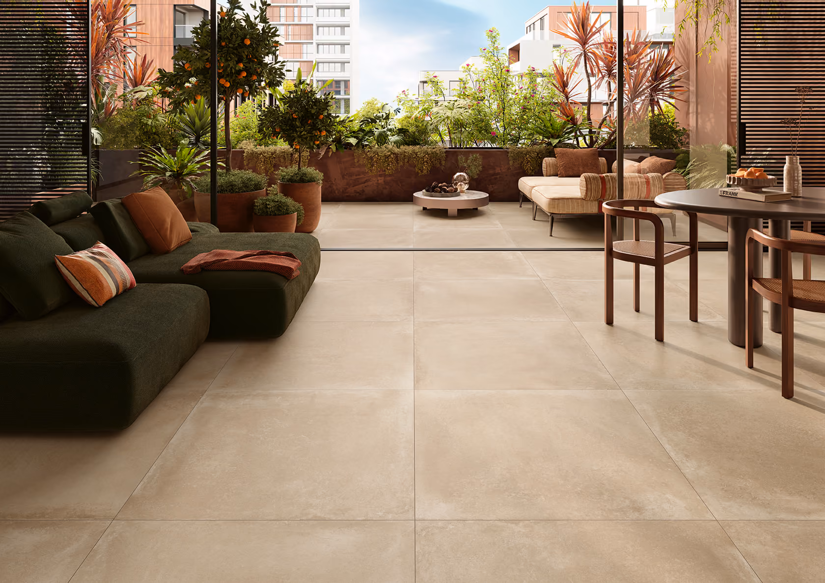 Modern outdoor patio with beige tiled floor, cozy sofas, wooden chairs, a round table, and lush plants.