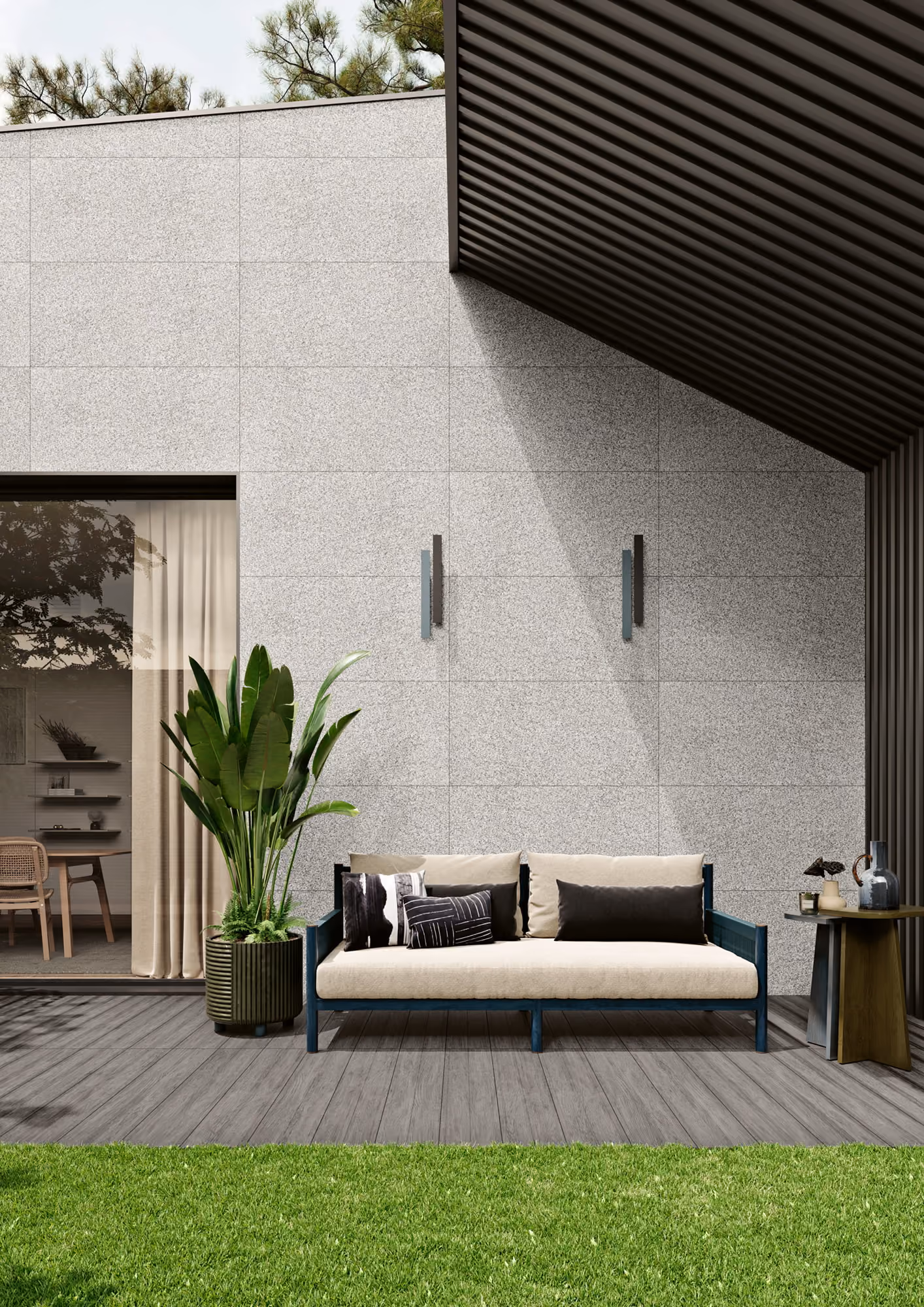 Modern outdoor seating area with a beige sofa, potted plant, side table, and grass lawn.