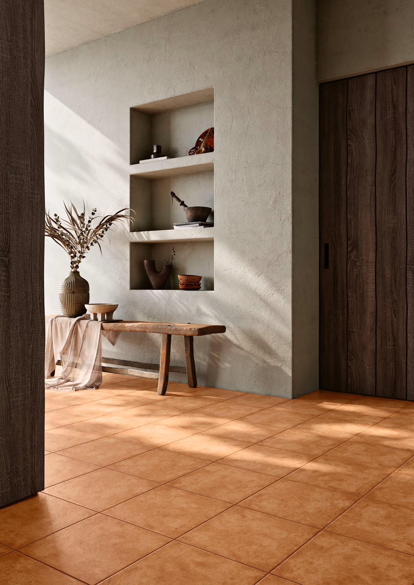Rustic interior with terracotta tile floor, wooden bench, wall niches with pottery, and decorative vase.