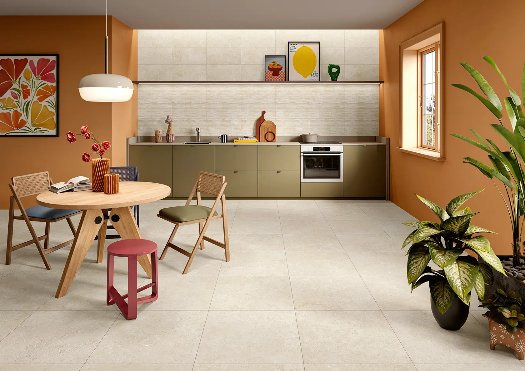 Modern kitchen with olive-green cabinets, round wooden table, chairs, and plants by orange walls.