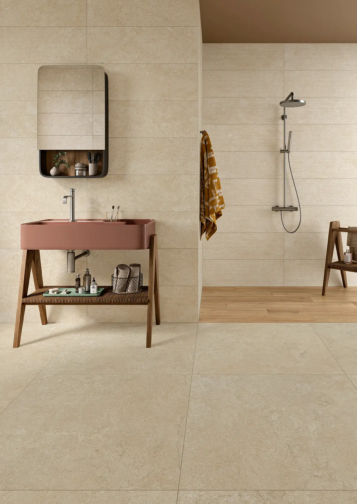 Modern beige tiled bathroom with rust-colored sink, wooden accessories, and a walk-in shower area.