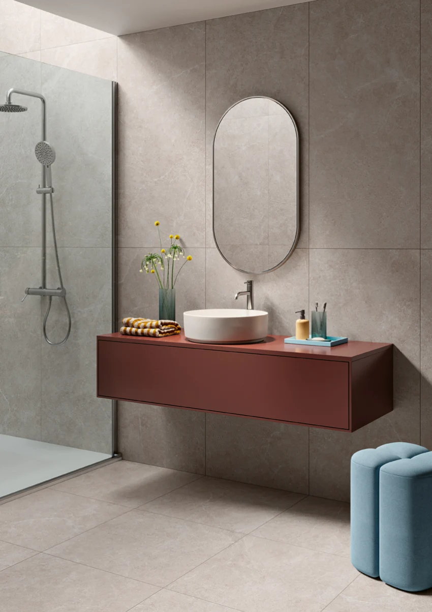 Modern bathroom with wall-mounted rust-colored vanity, oval mirror, round sink, and walk-in shower.