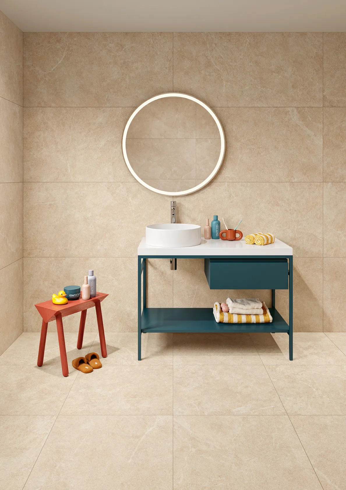 Modern bathroom with beige tile walls, round mirror, teal vanity, and small red stool with toiletries.