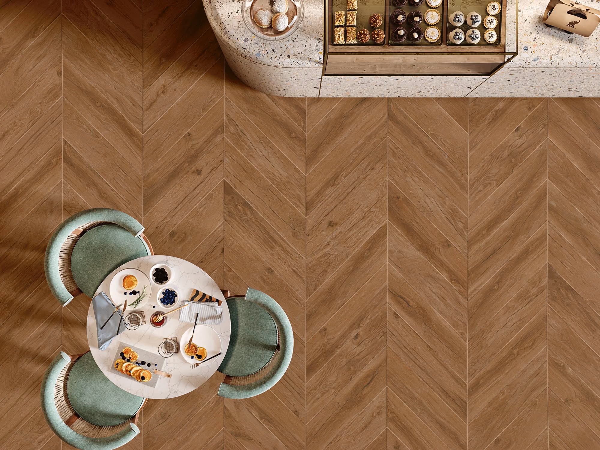 Top view of a round table with green chairs, pancakes, blueberries, and desserts on a wooden floor.