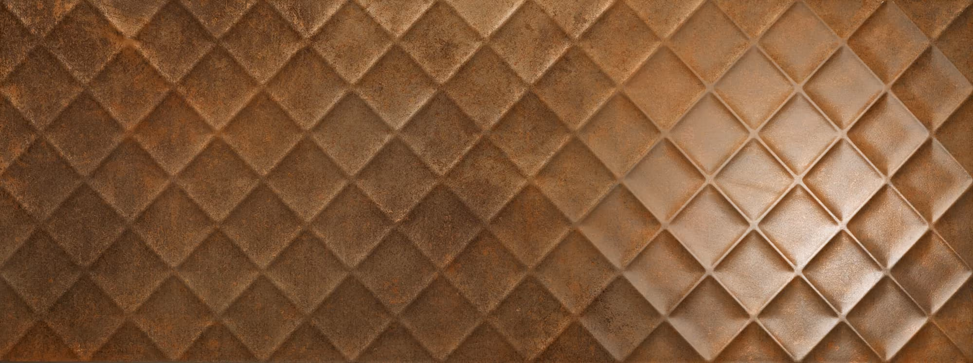 Textured metal surface with a diamond pattern fading from rusty brown to a lighter shade on the right.