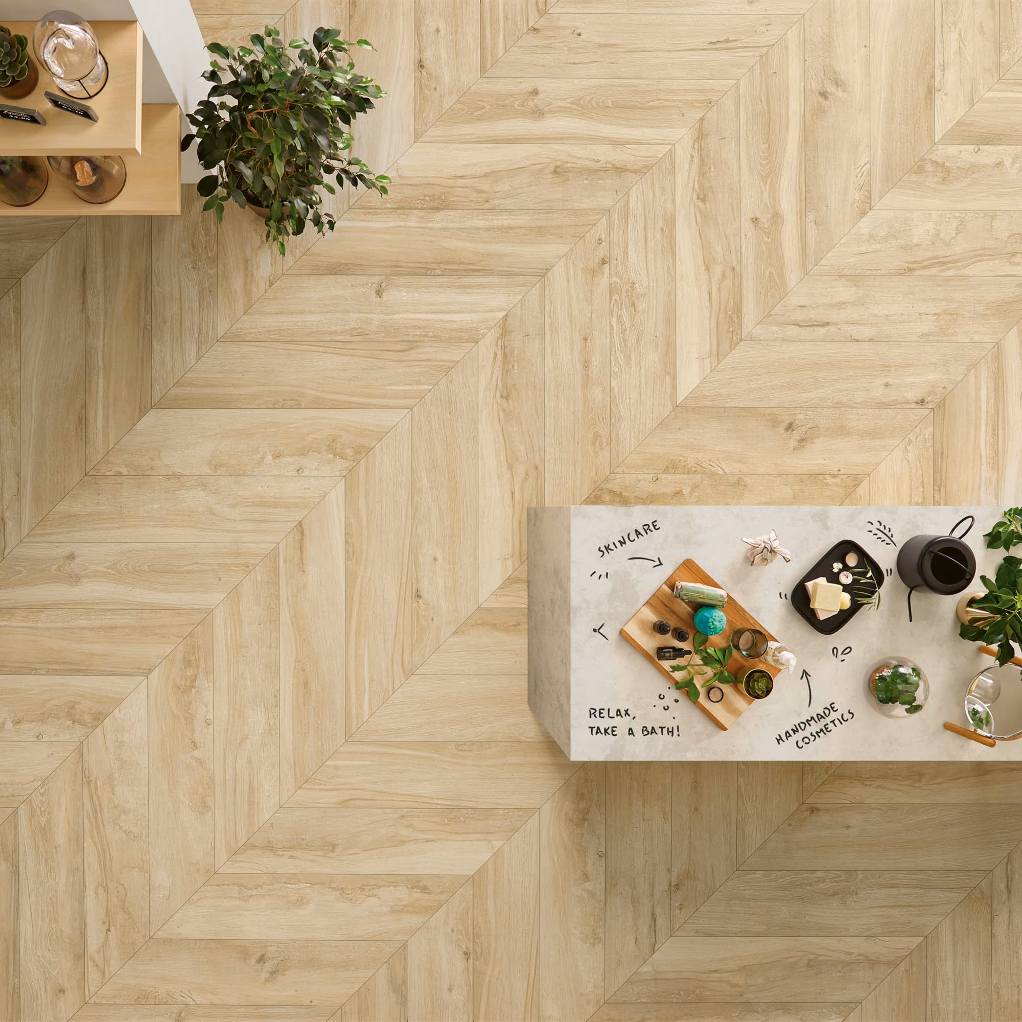 Top view of light wooden herringbone floor with cosmetics and plants on a marble table.