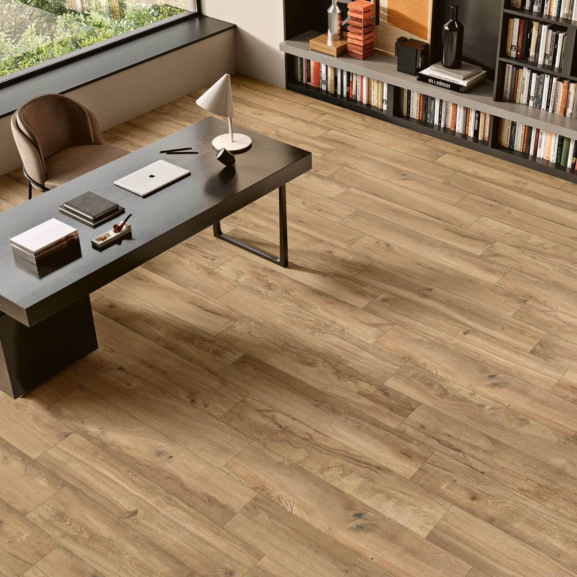 Modern office with wood-look plank flooring, black desk, brown chair, and a bookshelf.