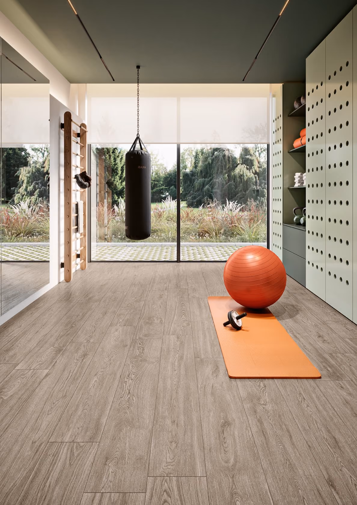 Home gym with wood flooring, a hanging punching bag, orange exercise ball, mat, and ab roller.