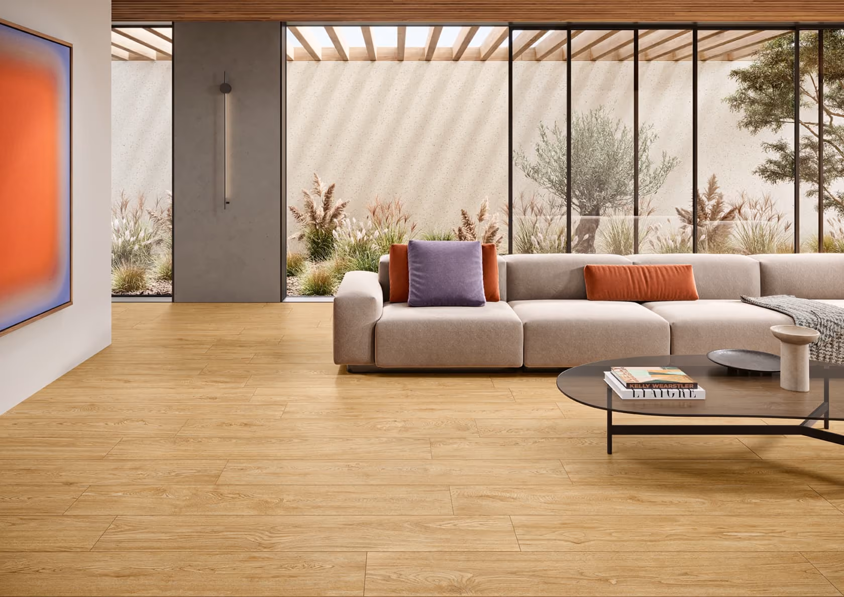 Modern living room with beige sofa, colorful cushions, wooden floor, and large glass wall with outdoor plants.