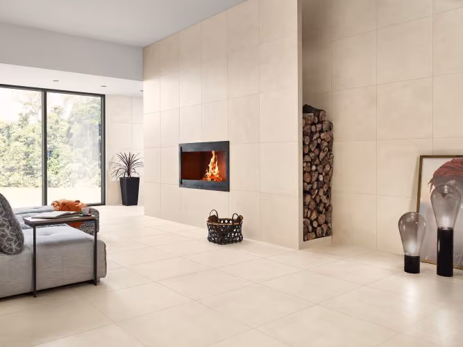 Modern living room with beige tile walls and floor, built-in fireplace, and a gray sofa near a glass door.