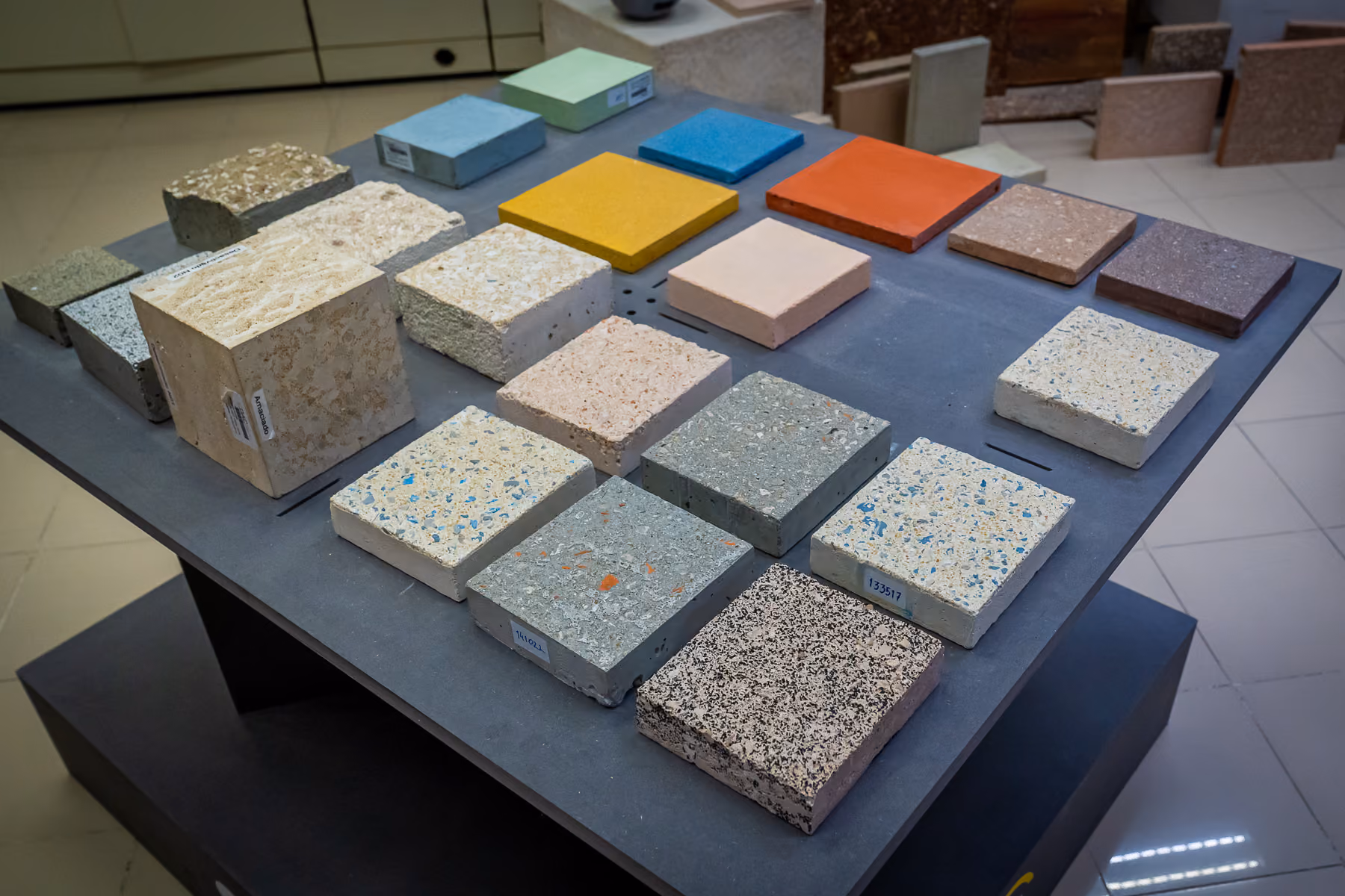 Varied colored and textured concrete and stone samples displayed on a table for comparison.