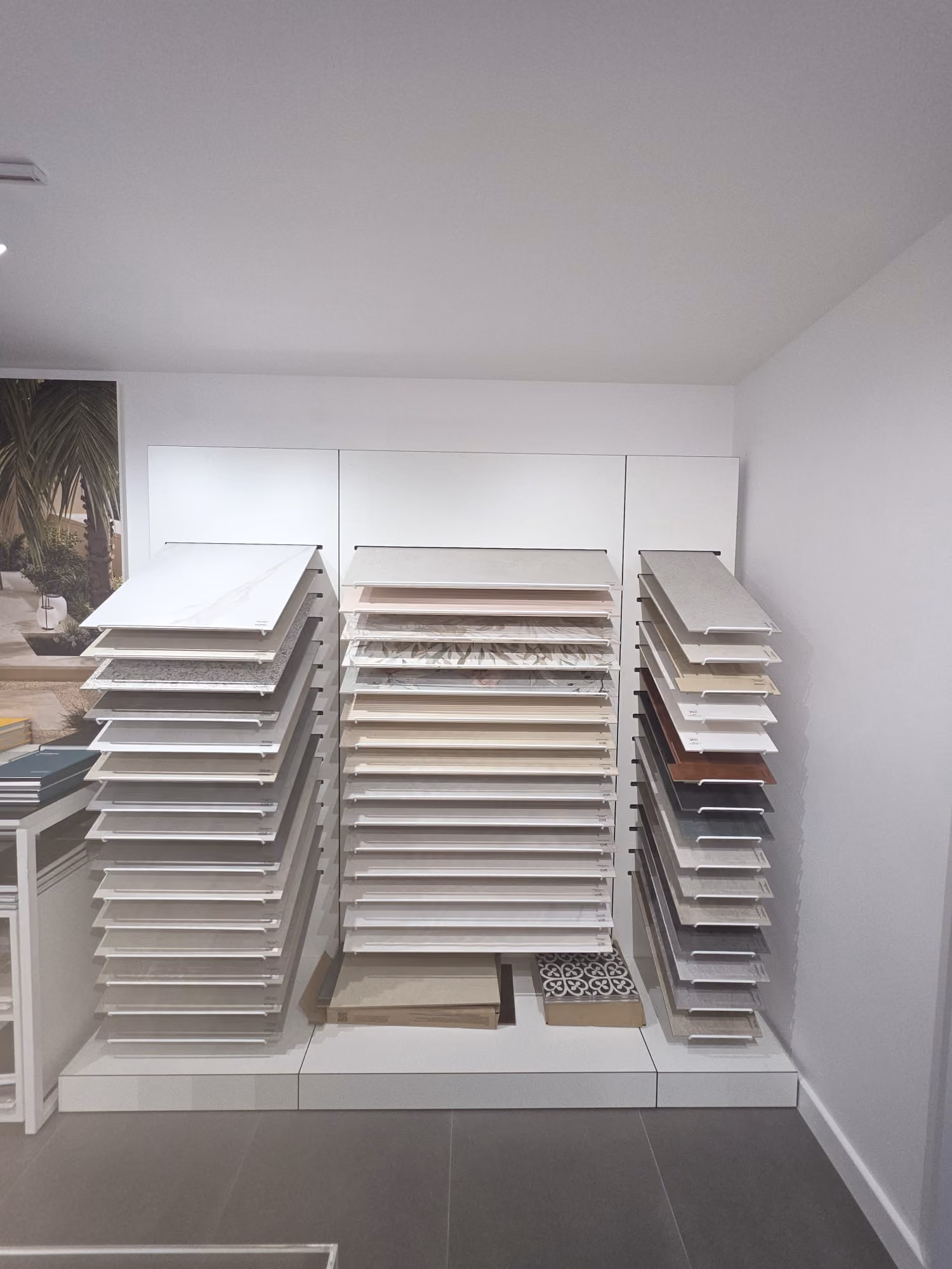 Display of ceramic tile samples in various shades of beige, gray, and white on racks.