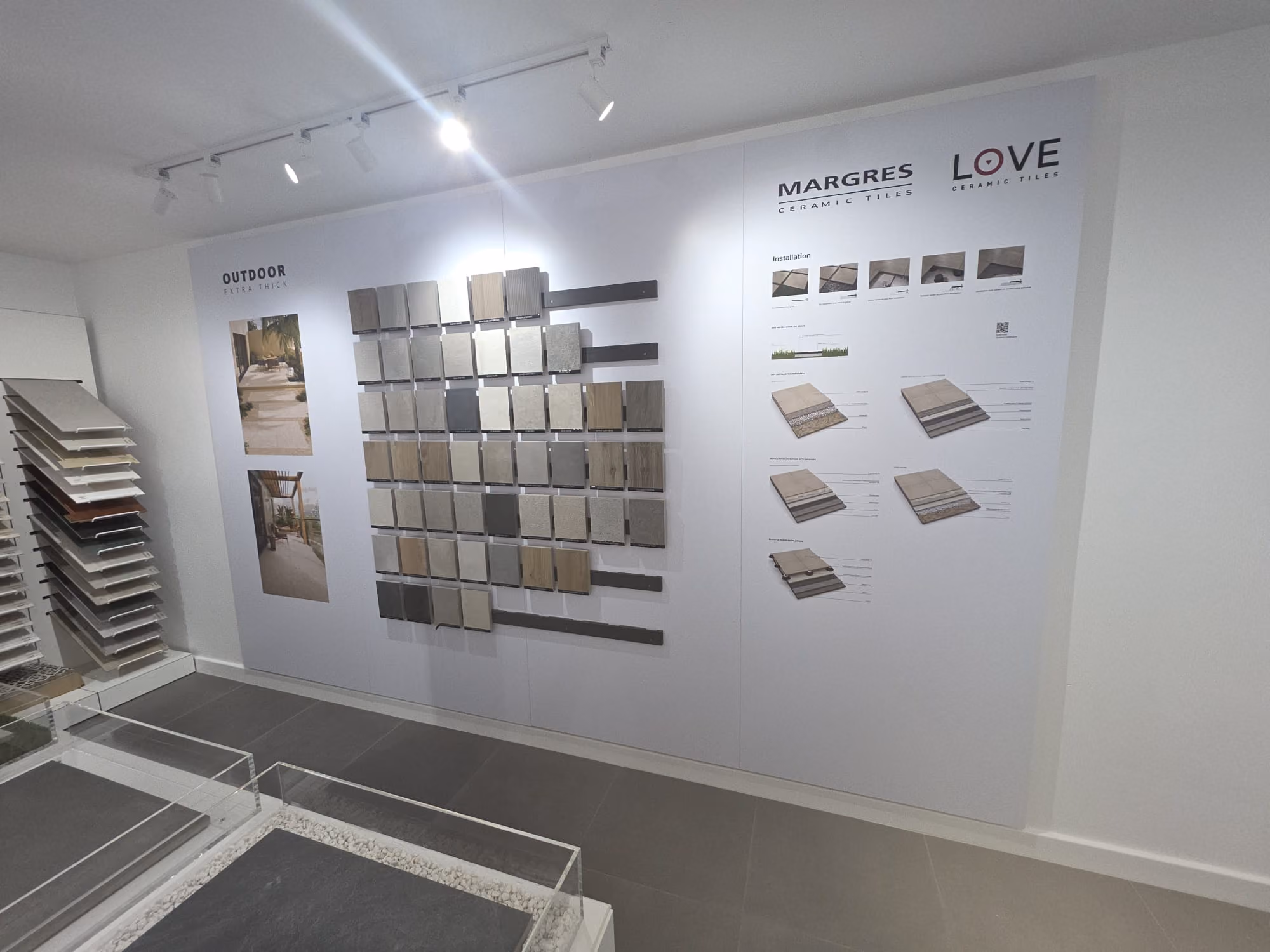 Wall display of various ceramic tile samples and installation guides in a showroom.