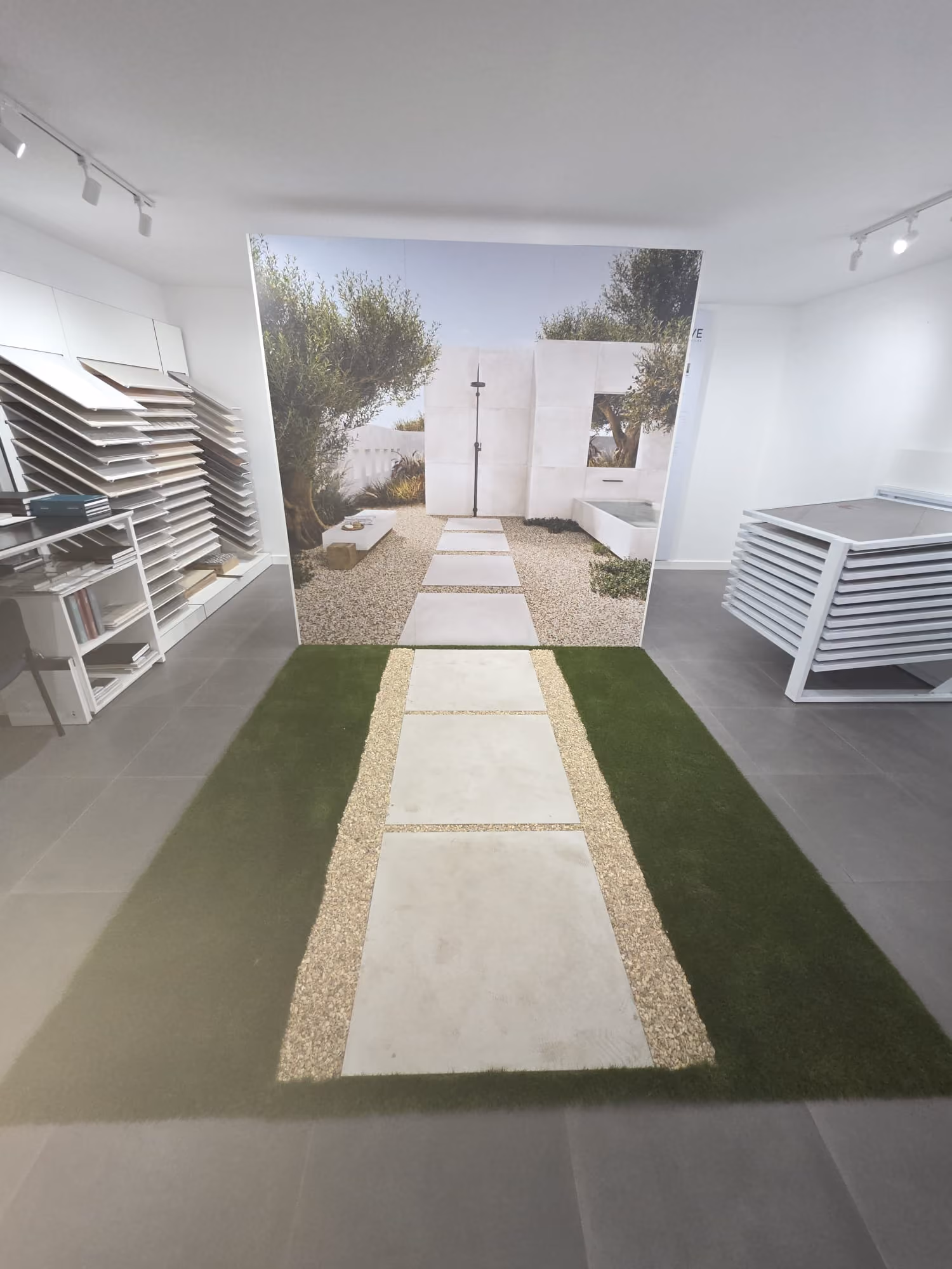 Indoor showroom with tile samples and a floor display of a garden path with stepping stones and grass.