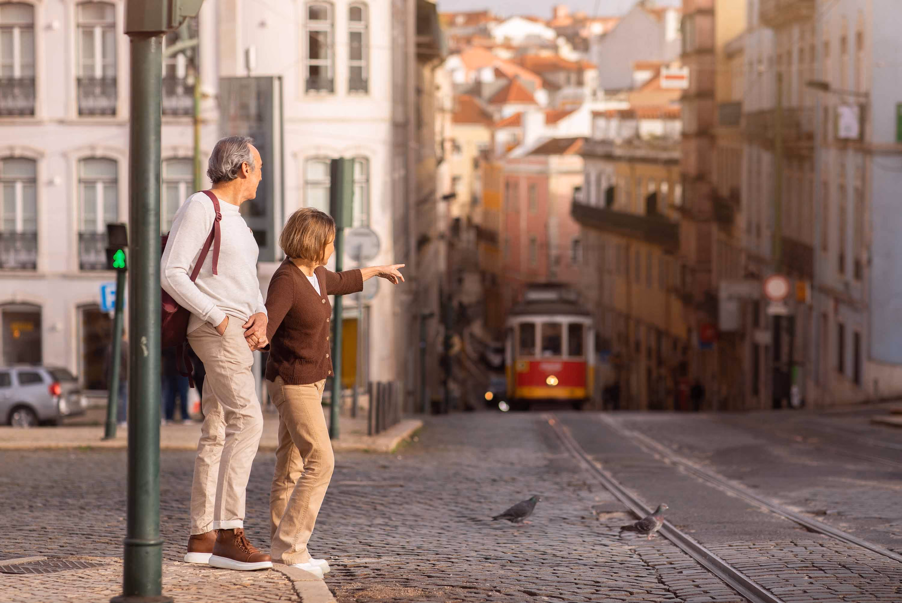 Elderly couple exploring Lisbon, pointing at a famous tram
