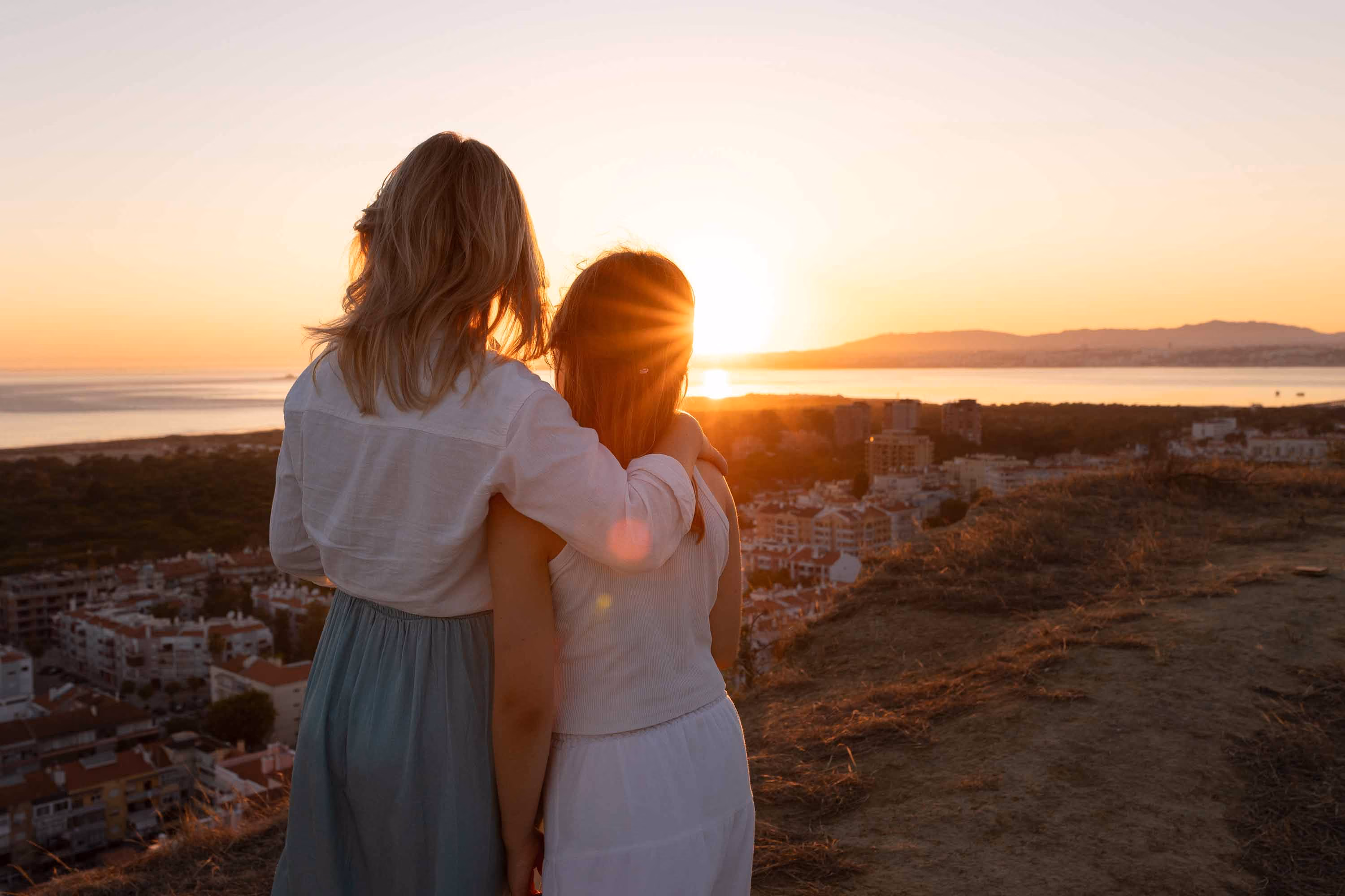 Mother and daughter enjoying the sunset over the sea in Portugal