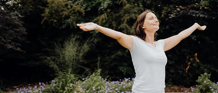 Woman standing with arms outstretched, representing relief and freedom from chronic symptoms